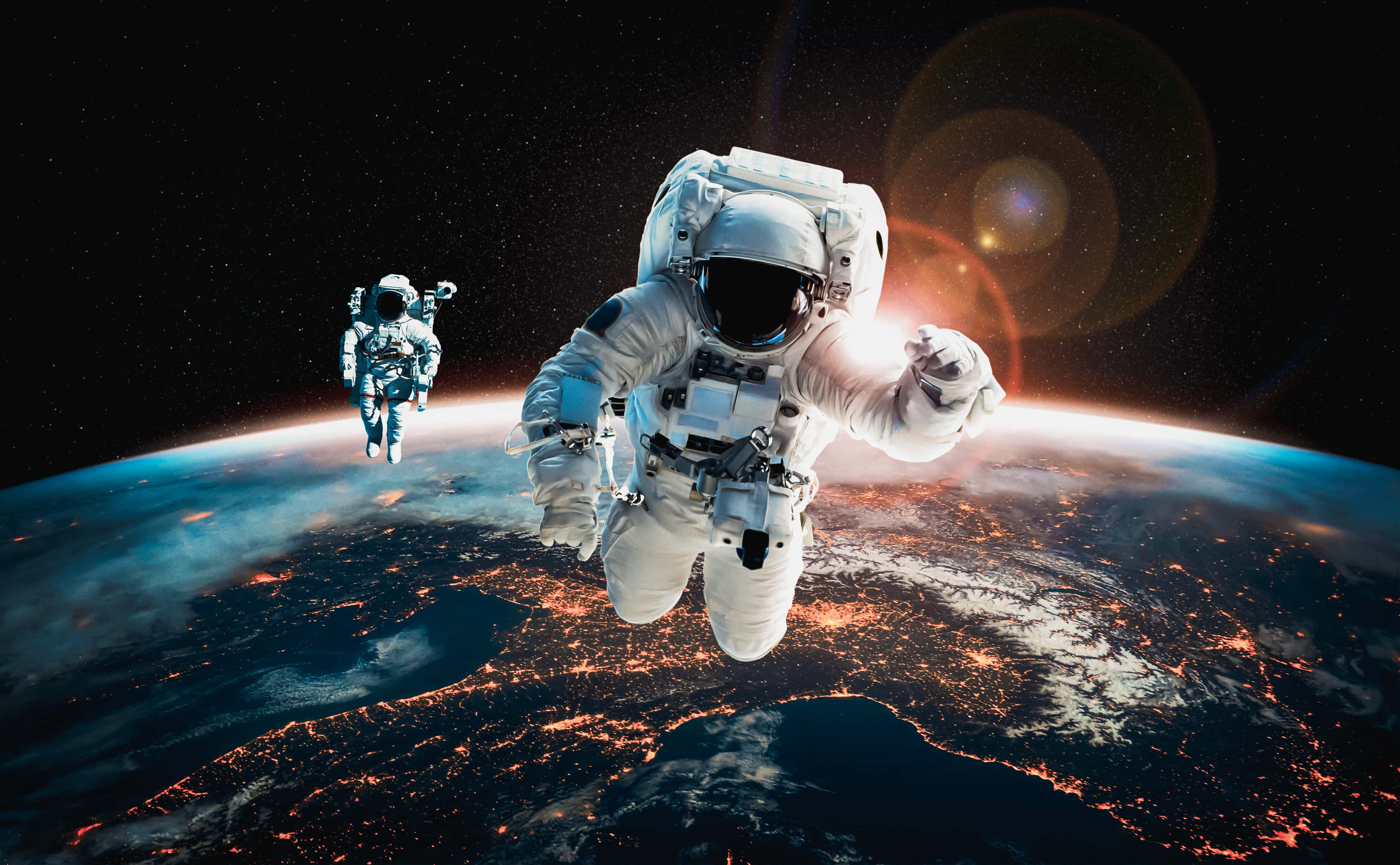 太空 桌布 壁紙 — 兩名太空人在太空中漂浮，下方是地球發光的城市燈光和彎曲的地平線。