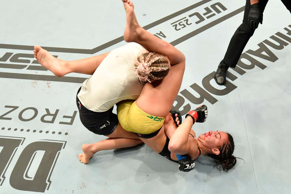 桌布 壁紙 — 兩名女性MMA拳手在UFC八角籠墊上進行冠軍賽時激烈纏鬥。