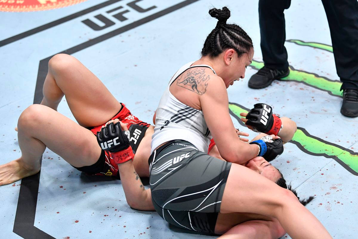MMA 桌布 壁紙 — 兩名女性MMA拳手在UFC八角籠墊上激烈纏鬥，可見血跡斑斑。
