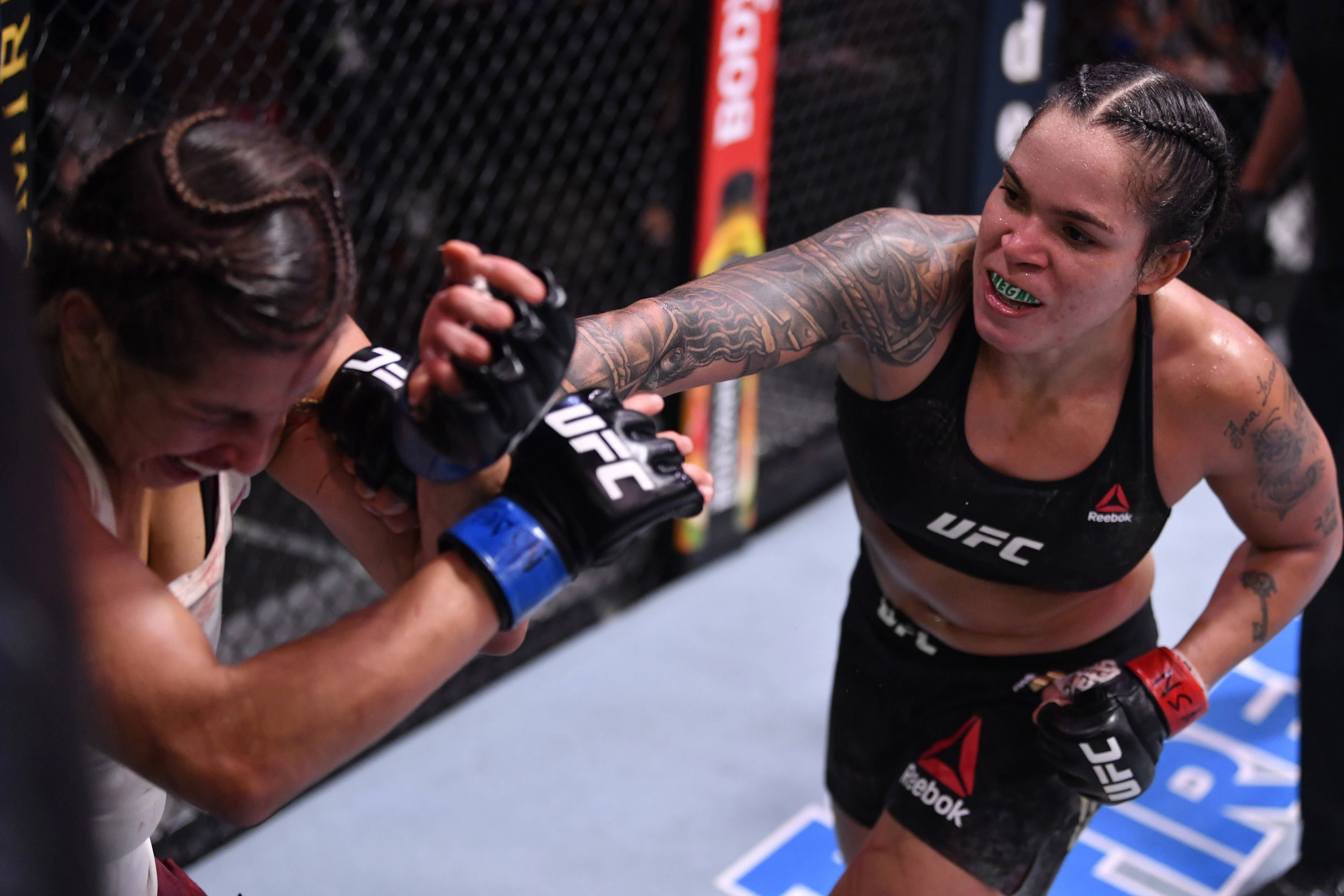 MMA 桌布 壁紙 — 兩名女性MMA拳手在UFC八角籠內激烈纏鬥，帶有刺青和專注的表情。