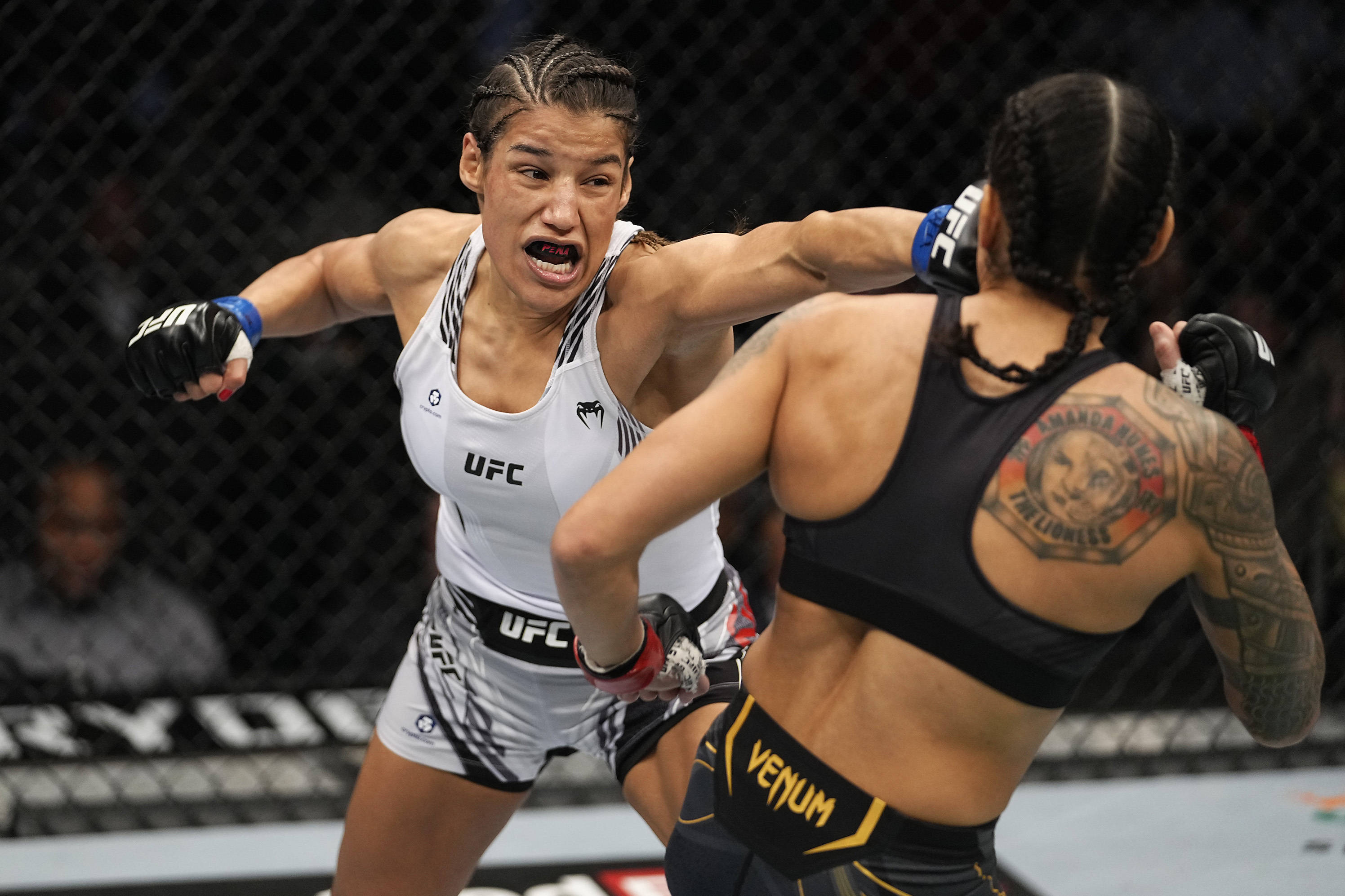 運動 桌布 壁紙 — 兩名女性MMA拳手在UFC八角籠內激烈交鋒，其中一人打出強力一拳。