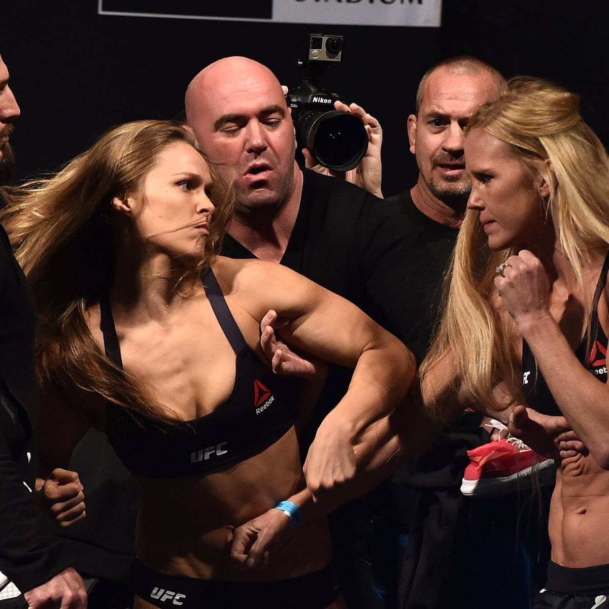 UFC 桌布 壁紙 — 兩名女性MMA拳手在官員和攝影師的包圍下，在稱重時激烈對峙。