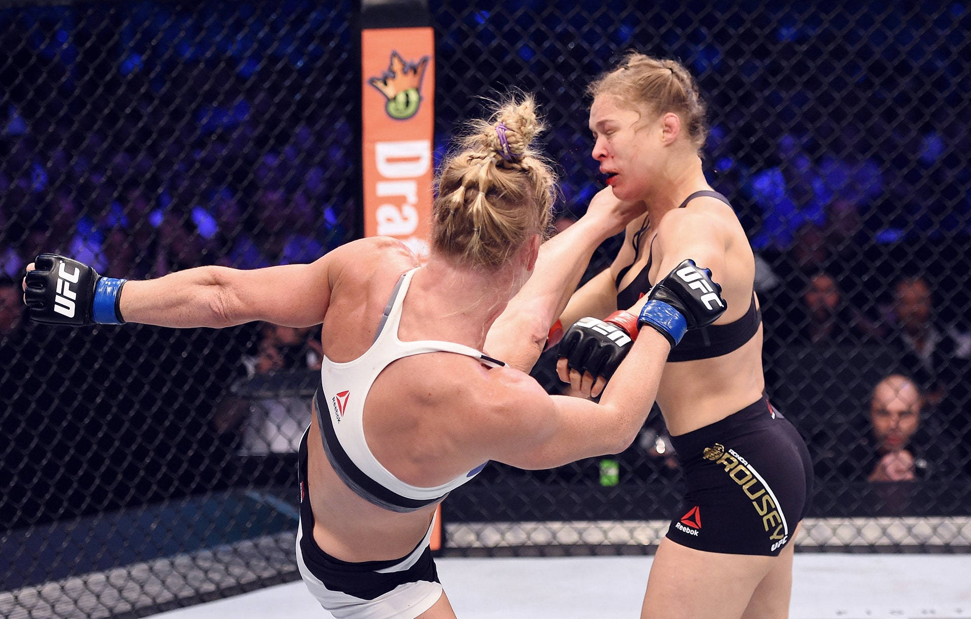 MMA 桌布 壁紙 — 兩名女性MMA拳手在明亮的場館燈光下，於UFC八角籠內激烈纏鬥。