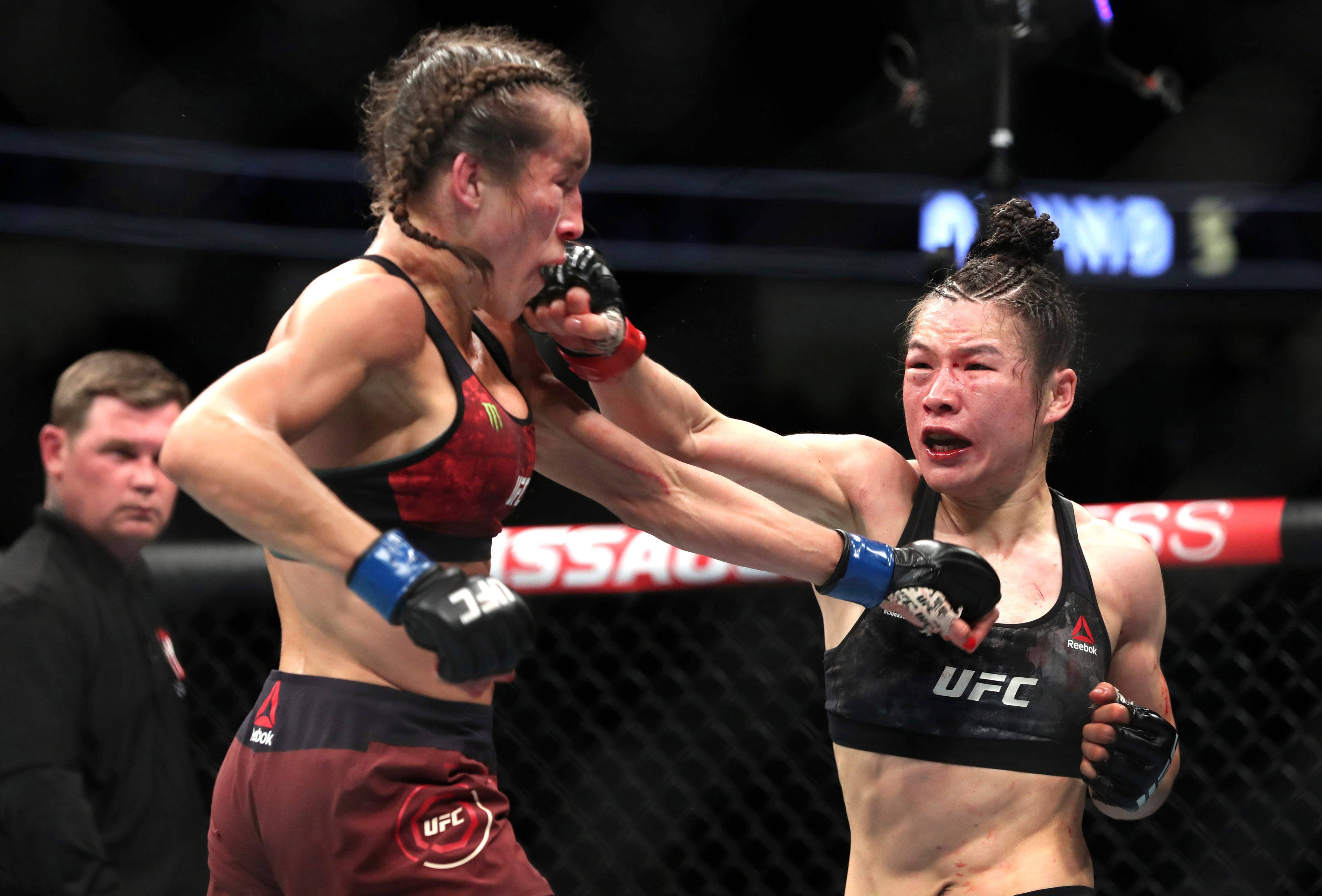 Celebrity 桌布 壁紙 — 兩名女性MMA拳手在激烈的UFC比賽中交鋒，其中一人打出強力一拳，另一人則因痛苦而扭曲表情。