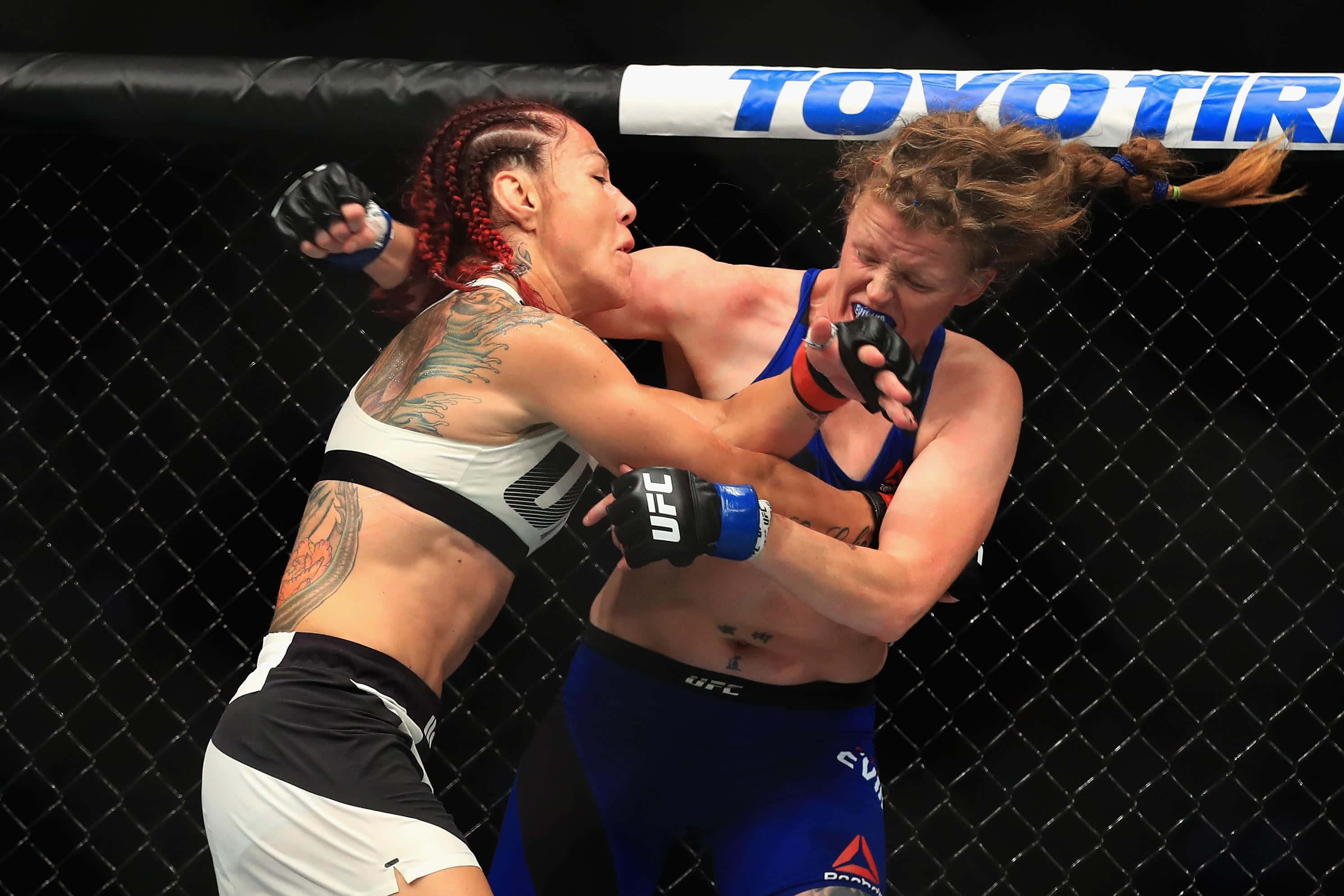 UFC 桌布 壁紙 — 兩名女性MMA拳手在激烈的鐵籠賽中交鋒，刺青和手套飛舞。