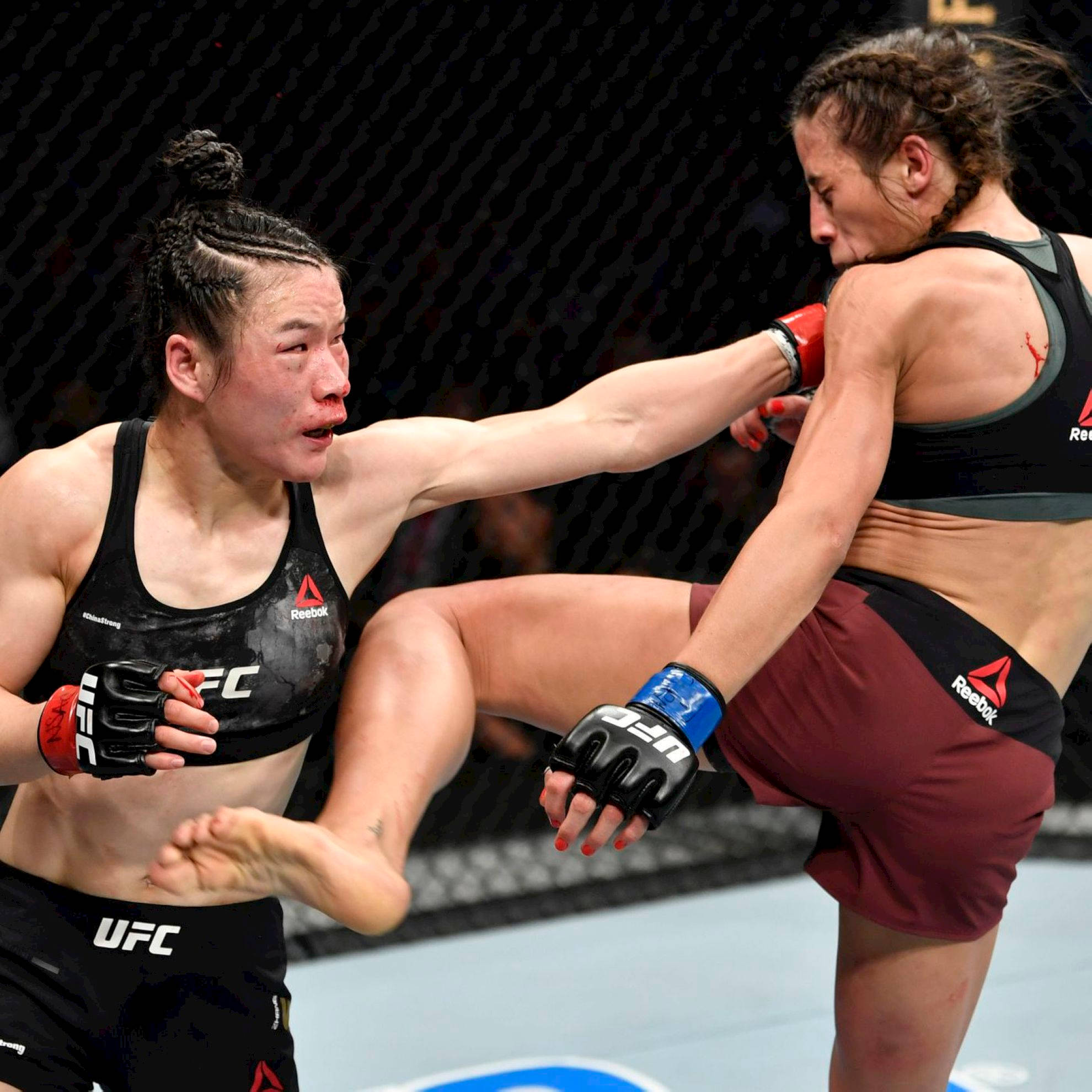 Punch 桌布 壁紙 — 兩名女性MMA拳手在激烈的鐵籠賽中交鋒，其中一人使出高踢，另一人則準備抵擋衝擊。