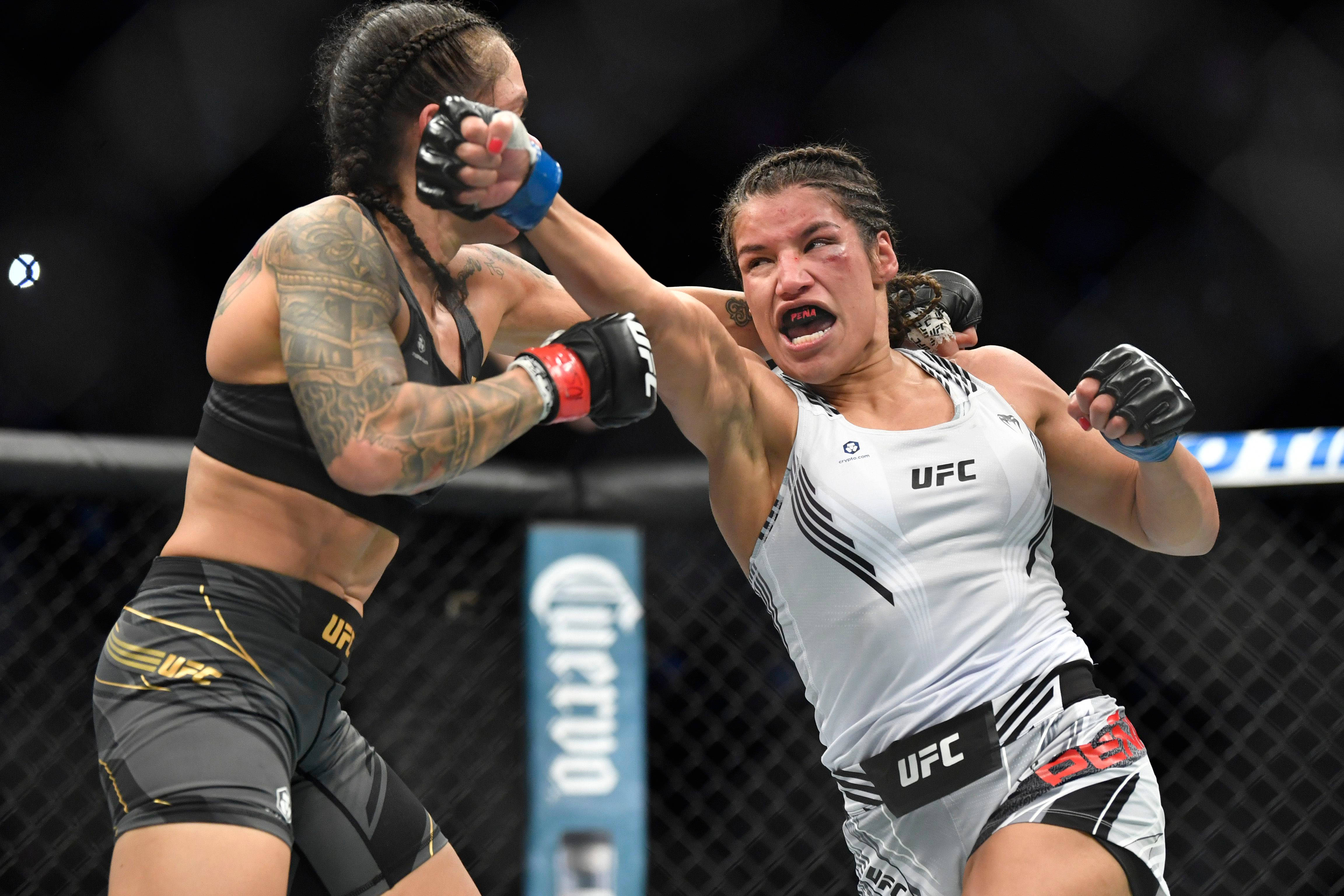 MMA 桌布 壁紙 — 兩名女性MMA拳手在激烈的鐵籠賽中交鋒，其中一人打出強力一拳。