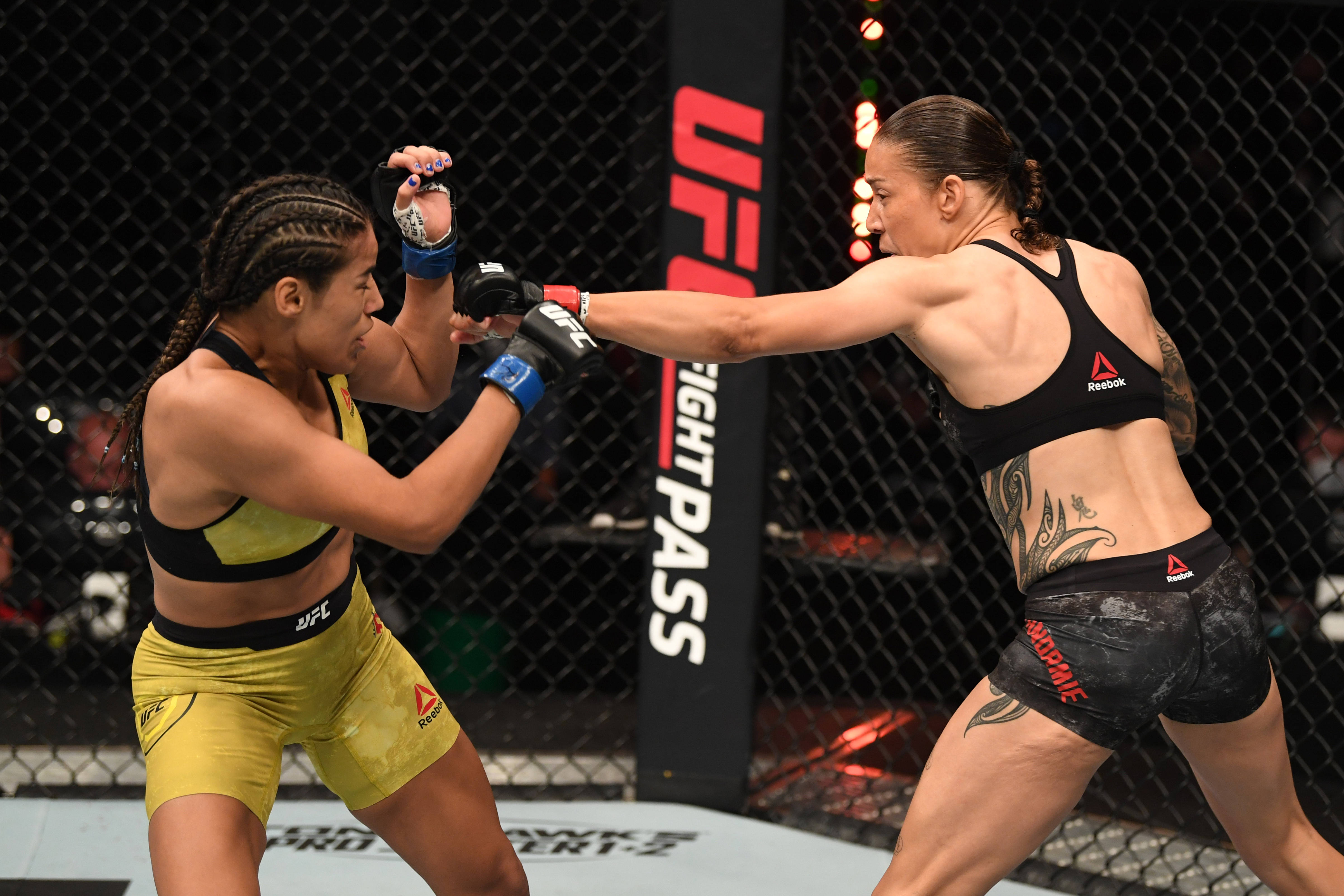 UFC 桌布 壁紙 — 兩名女性MMA拳手在籠中交鋒，一人出拳，另一人阻擋。