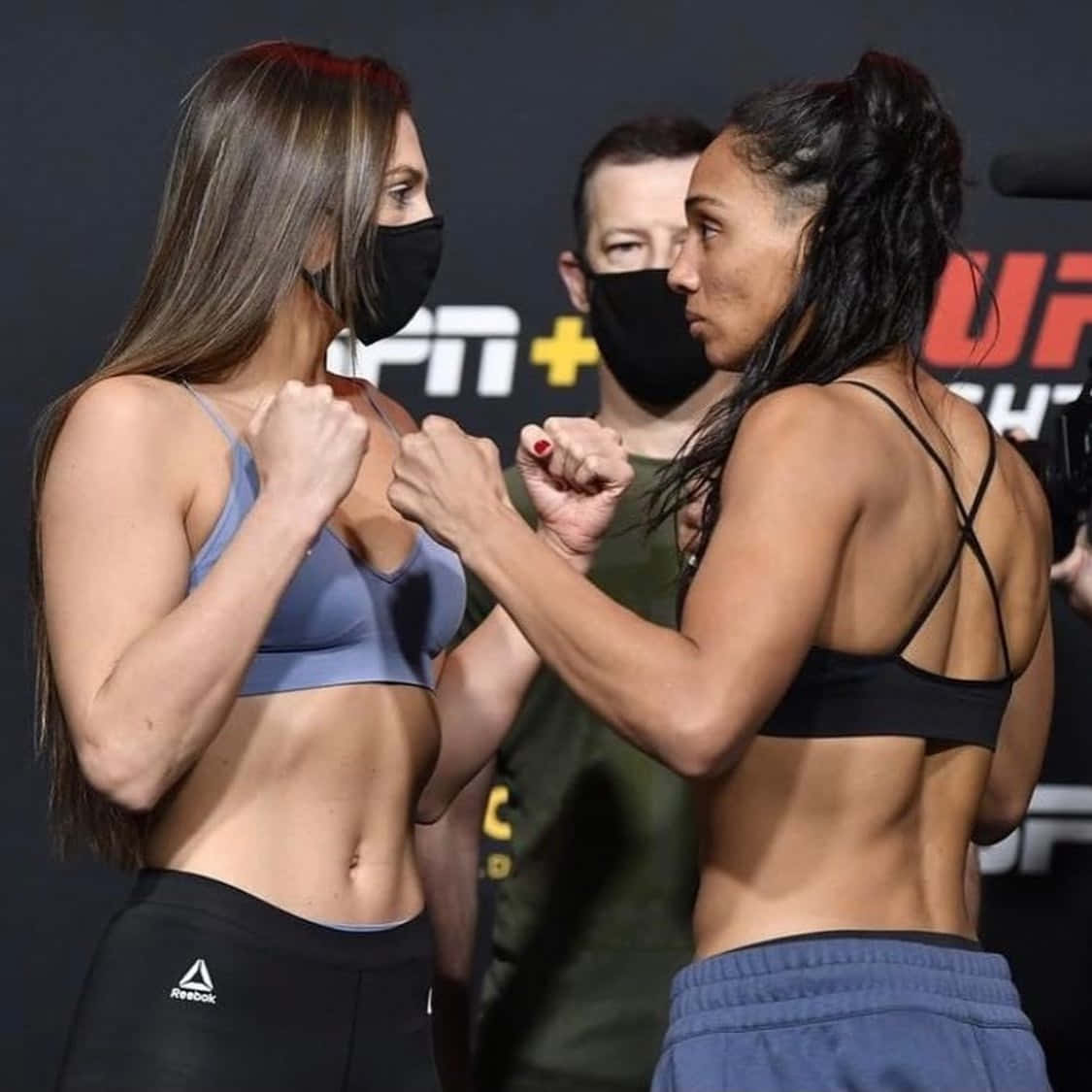 MMA 桌布 壁紙 — 兩名女性MMA拳手在緊張的賽前對峙中舉起拳頭。