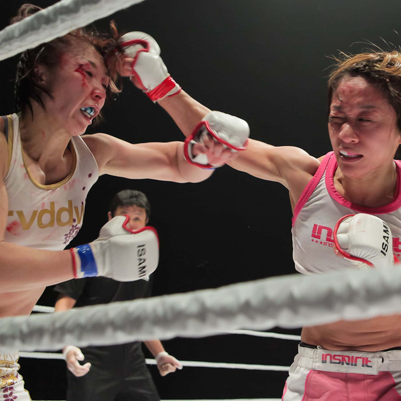 UFC 桌布 壁紙 — 兩名女拳擊手在一個粗糙的擂台上碰撞，臉上帶血，表情激烈，在明亮的燈光下。