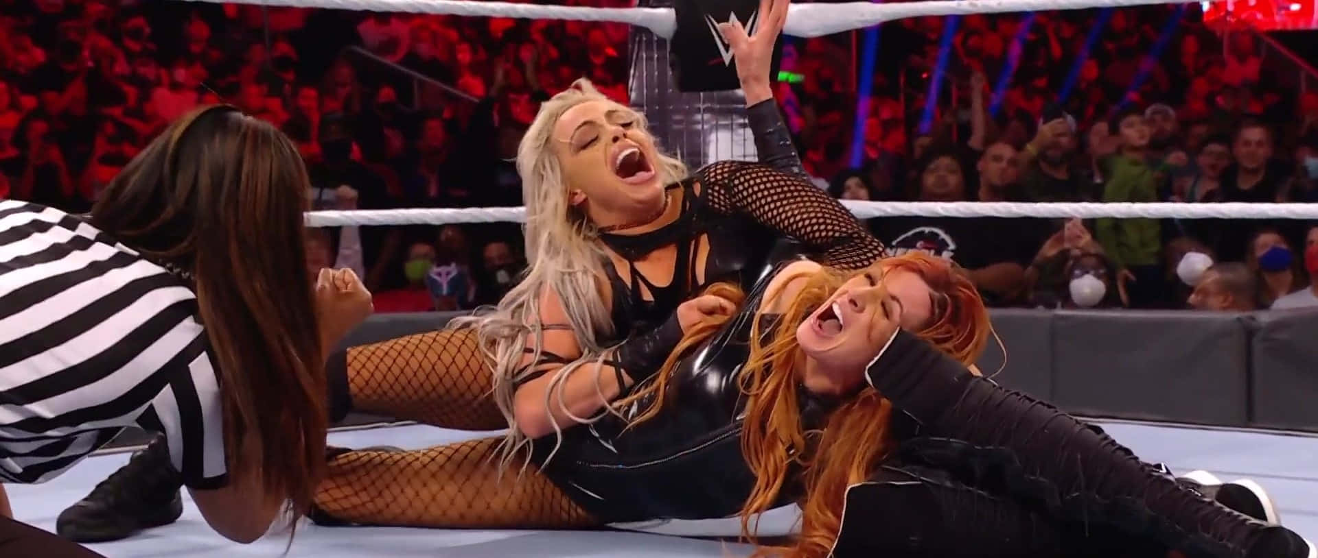 WWE 桌布 壁紙 — 兩名女摔角手在擂台上激烈纏鬥，裁判在旁觀看，身後觀眾歡呼。