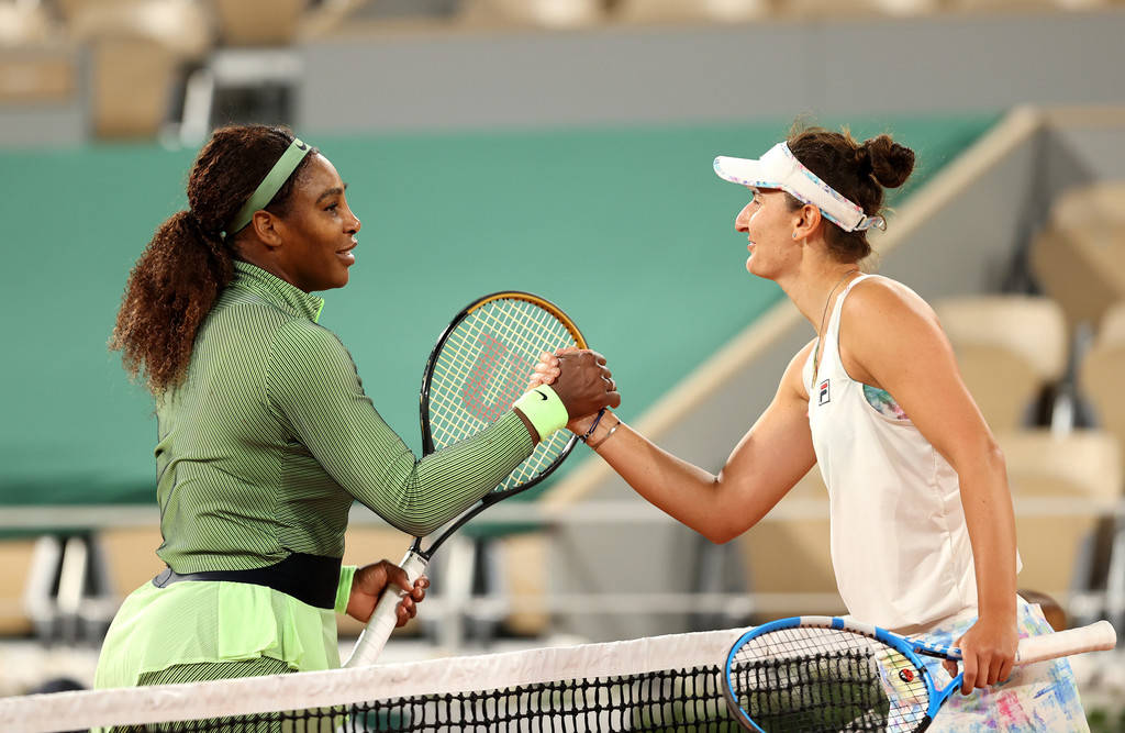 Tennis 桌布 壁紙 — 兩名女網球選手在紅土球場的網前握手，背景是體育場座位。