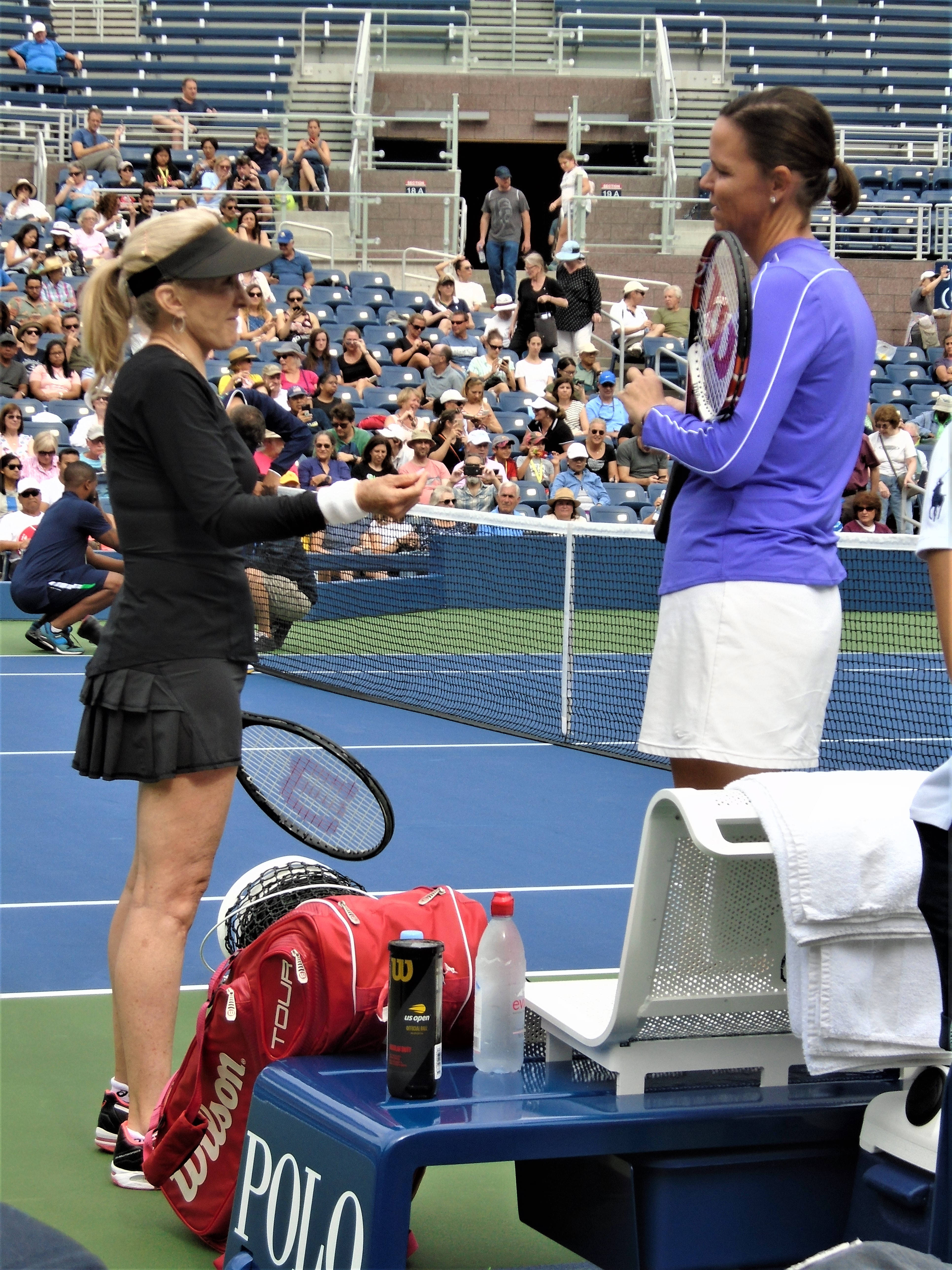 Tennis 桌布 壁紙 — 兩名女網球選手在藍色球場上握手，身後是體育場座位上的觀眾。
