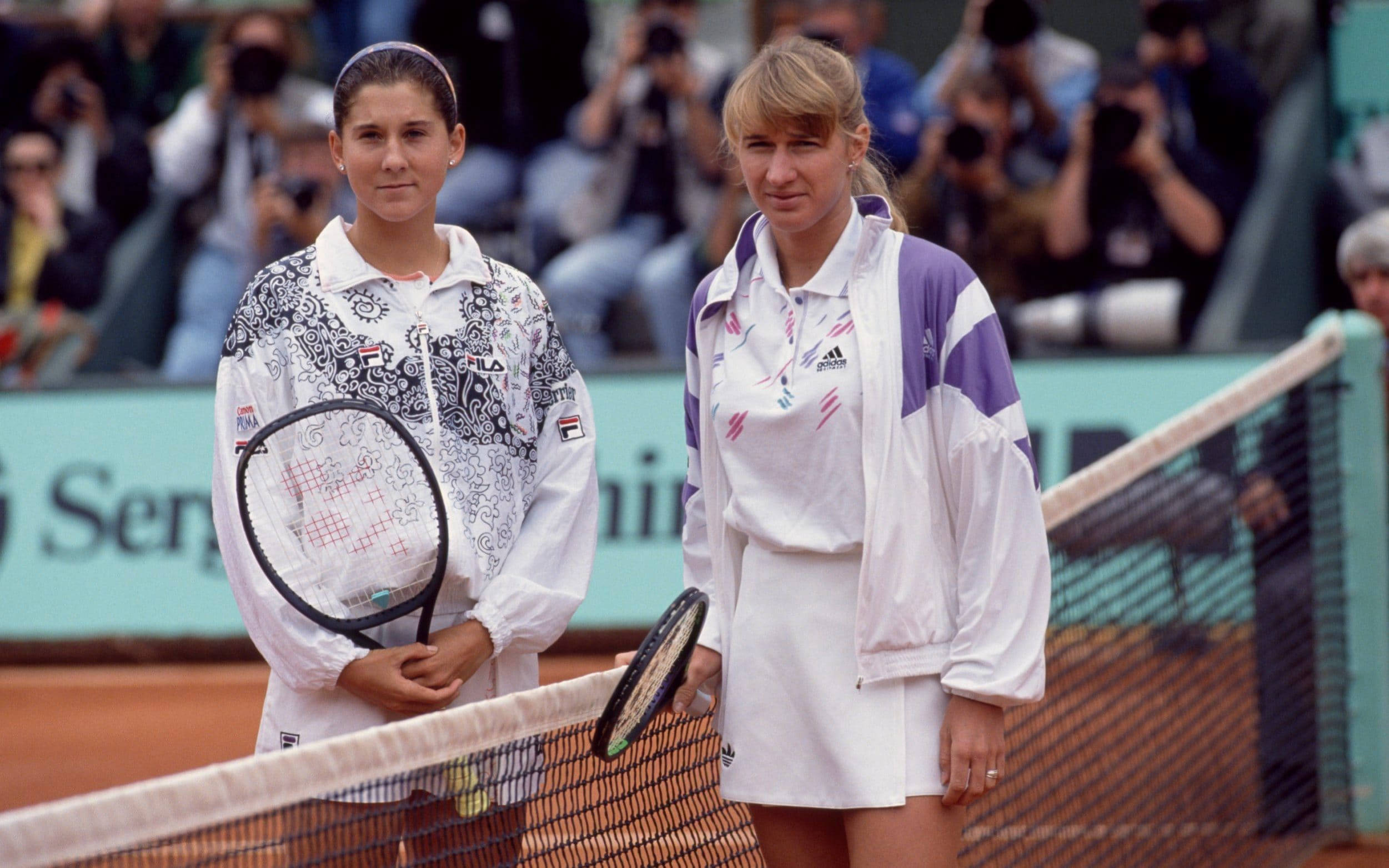 Monica Seles 桌布 壁紙 — 兩名女網球選手站在紅土球場的網前，背景有攝影師。