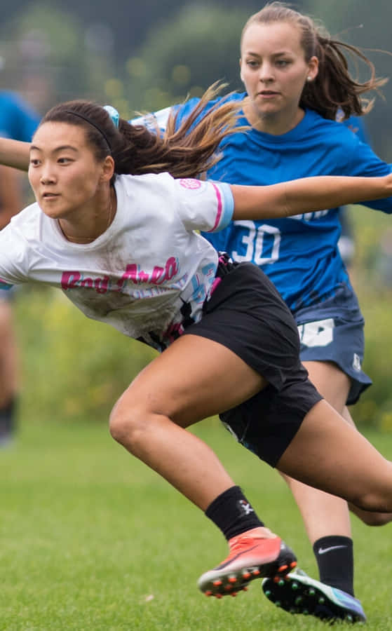 運動 桌布 壁紙 — 兩名女運動員在競爭激烈的戶外體育比賽中，在草地上全力衝刺。