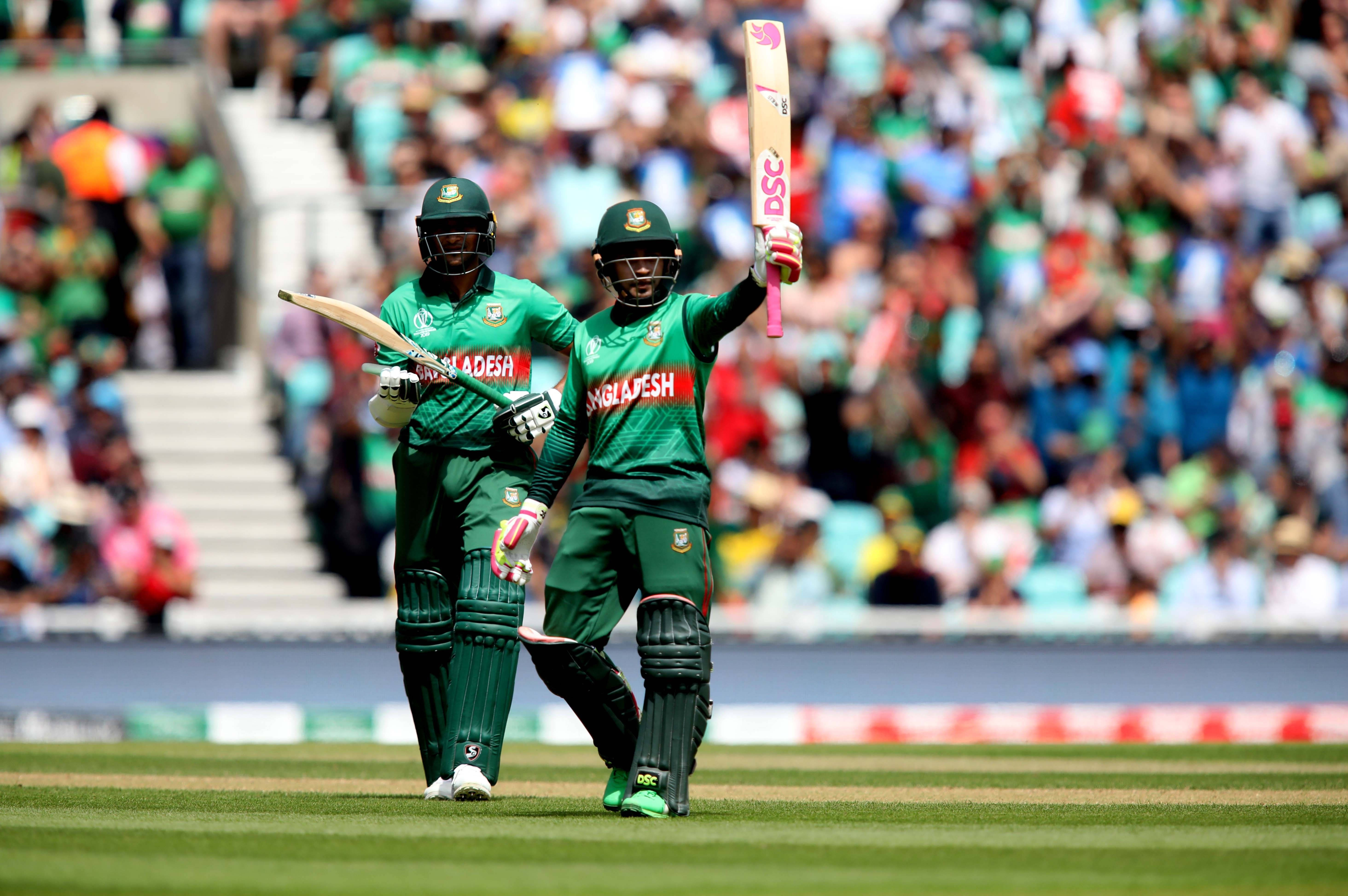 Bangladesh Cricket 桌布 壁紙 — 兩名孟加拉國板球運動員在陽光明媚的球場上高舉球棒，在歡呼的人群面前慶祝。