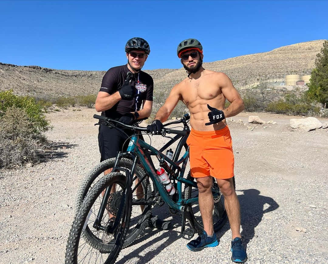 Athlete 桌布 壁紙 — 兩名山地車手在晴朗藍天下，於陽光普照的沙漠小徑上自信地與他們的單車擺姿勢。