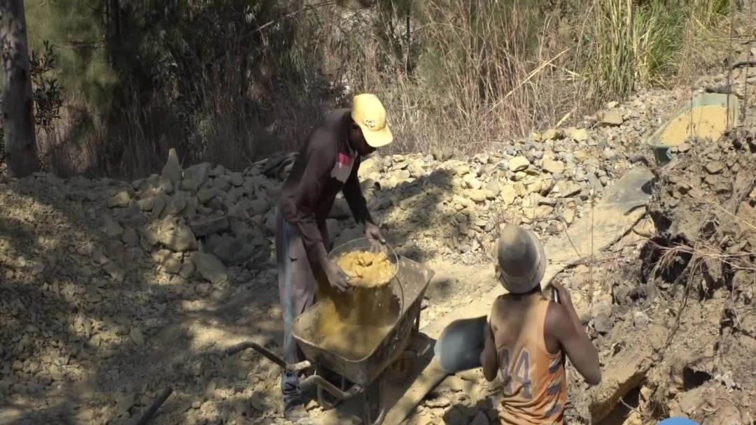 Mining 桌布 壁紙 — 兩名工人在陽光普照的岩石戶外區域，在碎石和乾燥植被環繞下，將混凝土混合並裝入獨輪車。