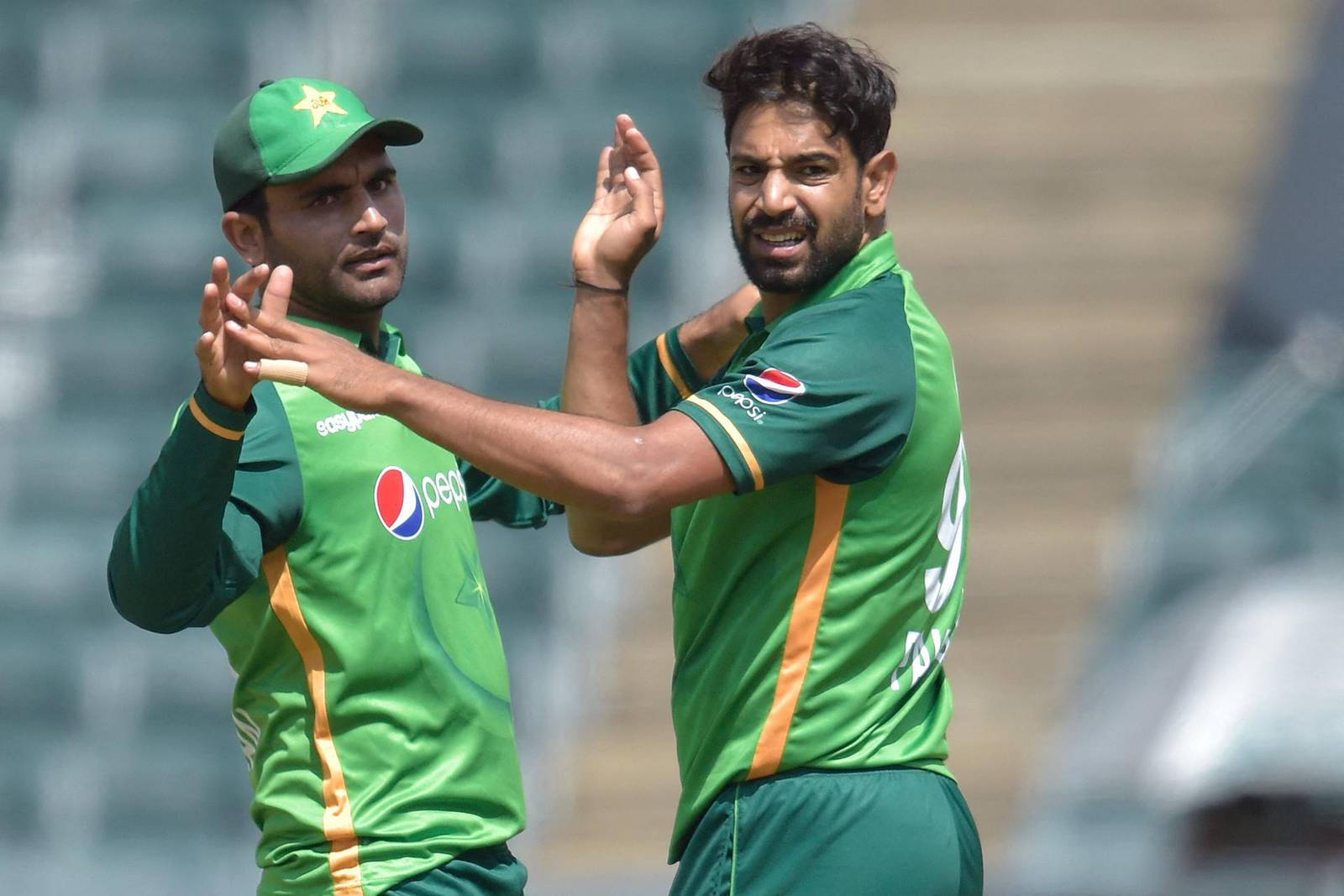 Fakhar Zaman 桌布 壁紙 — 兩名巴基斯坦板球運動員身穿綠色制服，在陽光明媚的場地上擊掌慶祝。