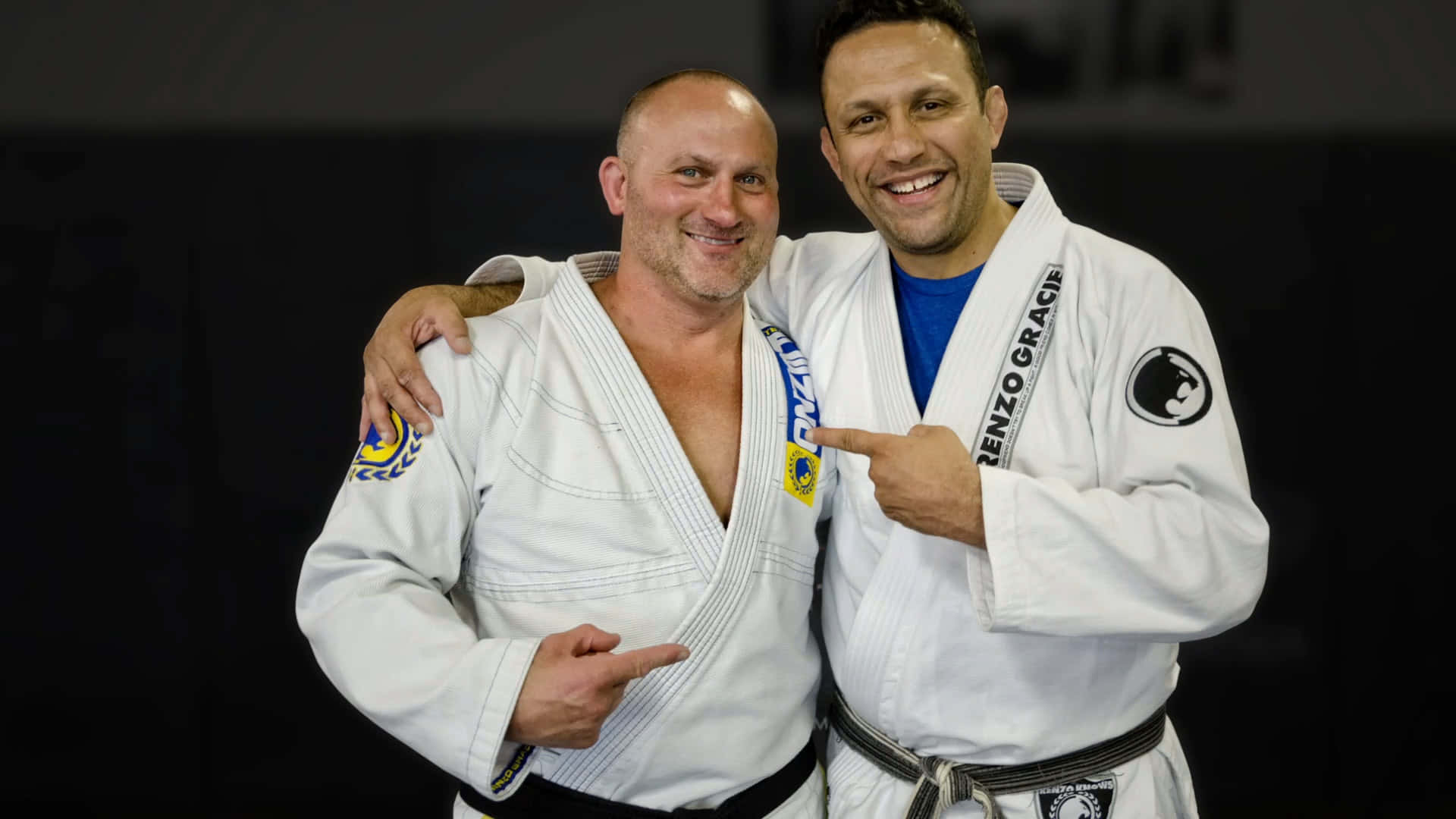 martial arts 桌布 壁紙 — 兩名微笑的巴西柔術選手穿著白色道服，在深色背景前自豪地擺姿勢。