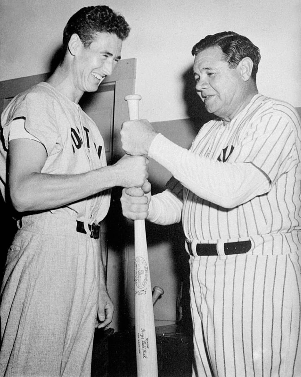 Ted Williams 桌布 壁紙 — 兩名微笑的棒球運動員穿著復古細條紋和素色制服，在室內歡樂時刻一起握著球棒。