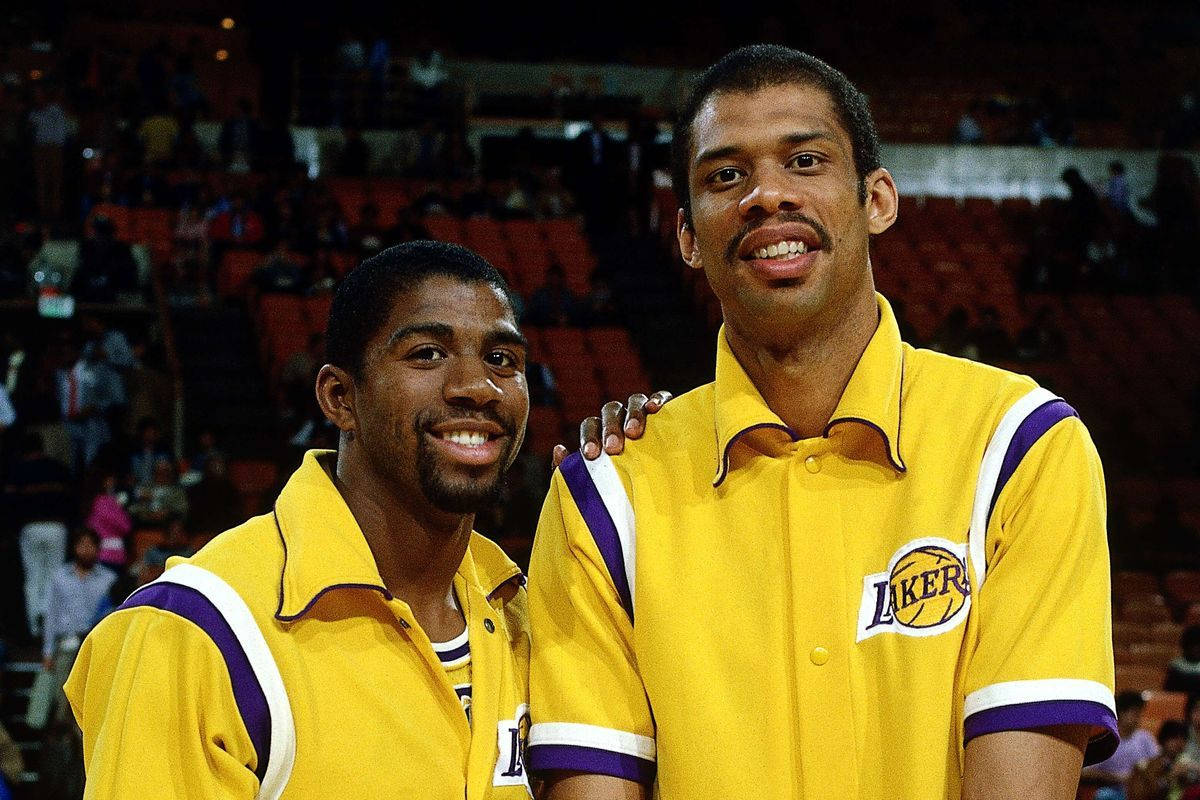Kareem 桌布 壁紙 — 兩名微笑的籃球運動員身穿黃色湖人隊熱身球衣，在擁擠的場館中互相搭肩合影。