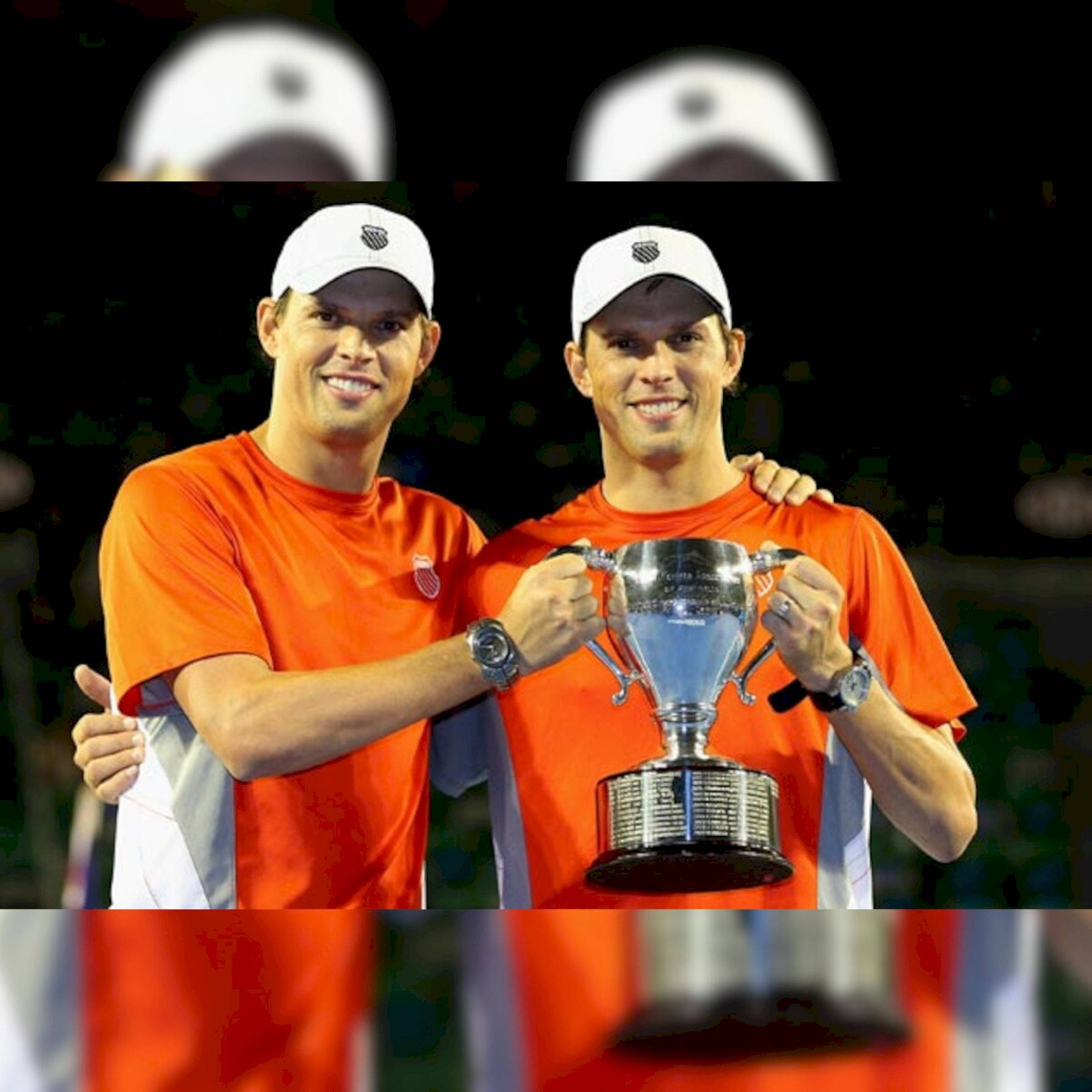 Trophy 桌布 壁紙 — 兩名微笑的網球運動員身穿橙色襯衫和白色帽子，在明亮的體育場燈光下自豪地共同舉起閃閃發光的銀色獎盃。