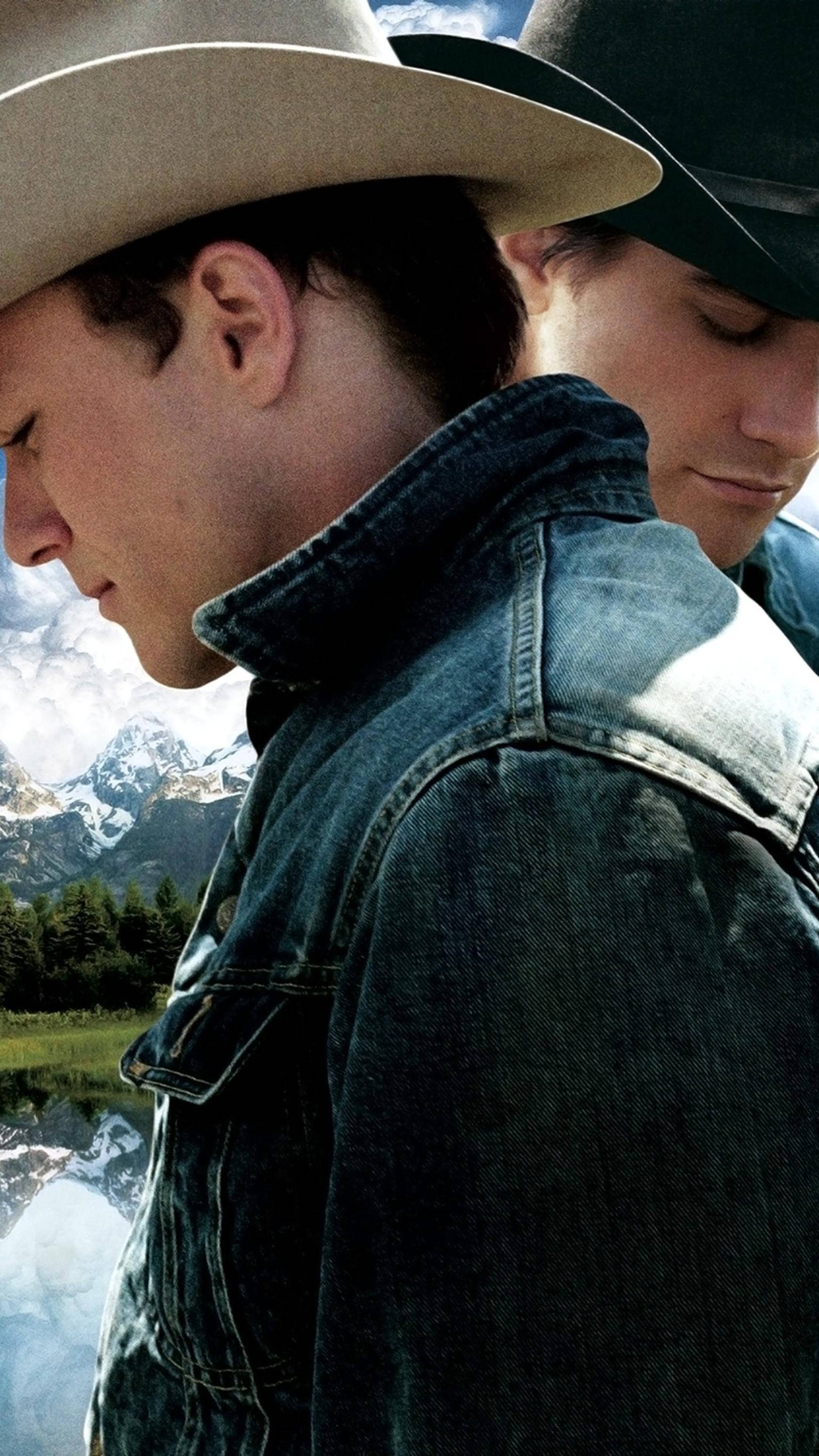 brokeback mountain 桌布 壁紙 — 兩名戴牛仔帽、穿牛仔夾克的男子，以雪山和倒映湖景為背景，側面站立。