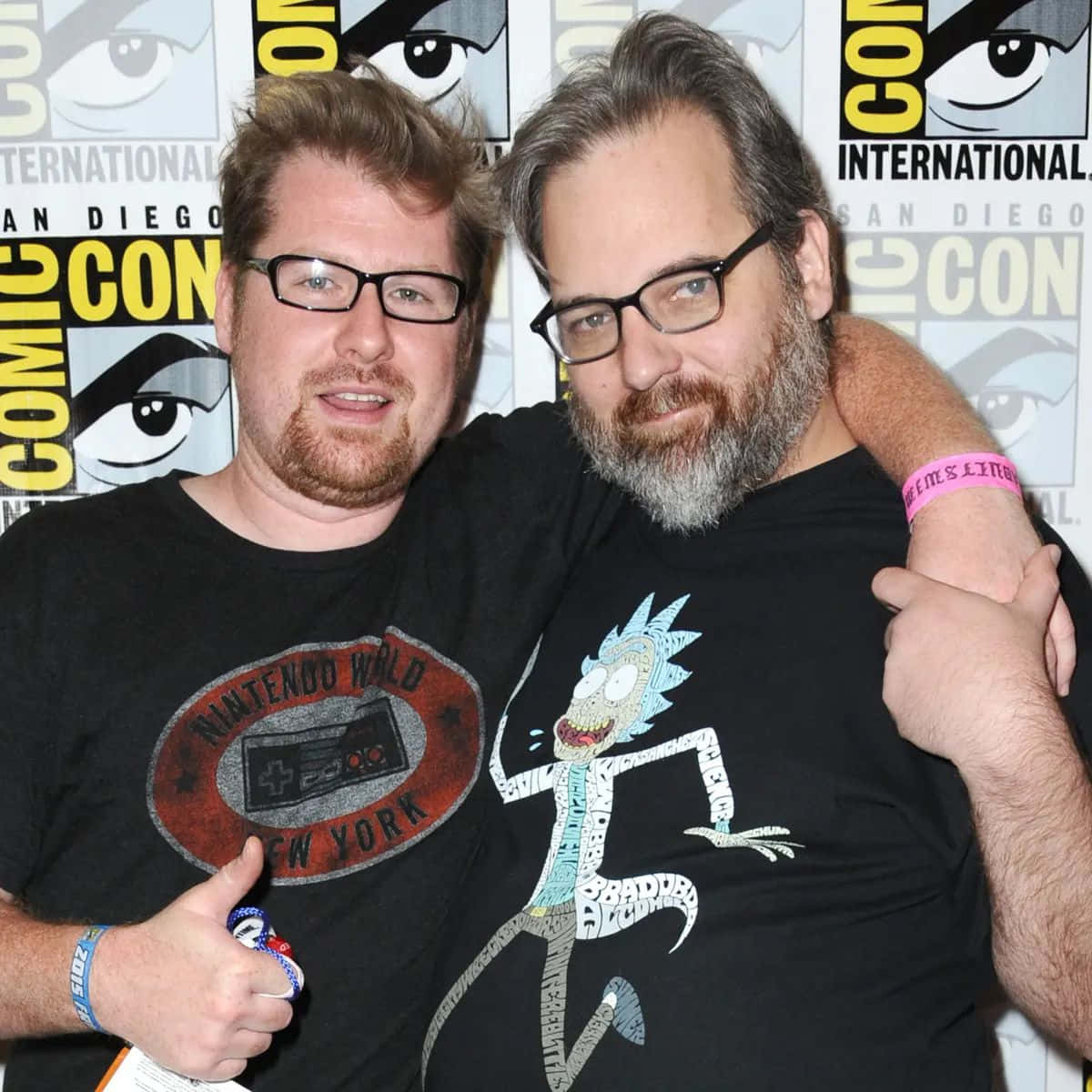 Justin Roiland 桌布 壁紙 — 兩名戴眼鏡留鬍鬚的男子在Comic-Con一起擺姿勢，穿著主題T恤，一件是Rick Sanchez，另一件是Nintendo World New York。