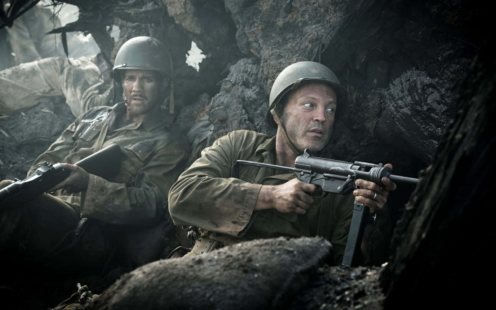 World War 2 桌布 壁紙 — 兩名戴著頭盔的疲憊士兵蹲在泥濘的戰壕中，帶著陰沉的決心瞄準步槍。