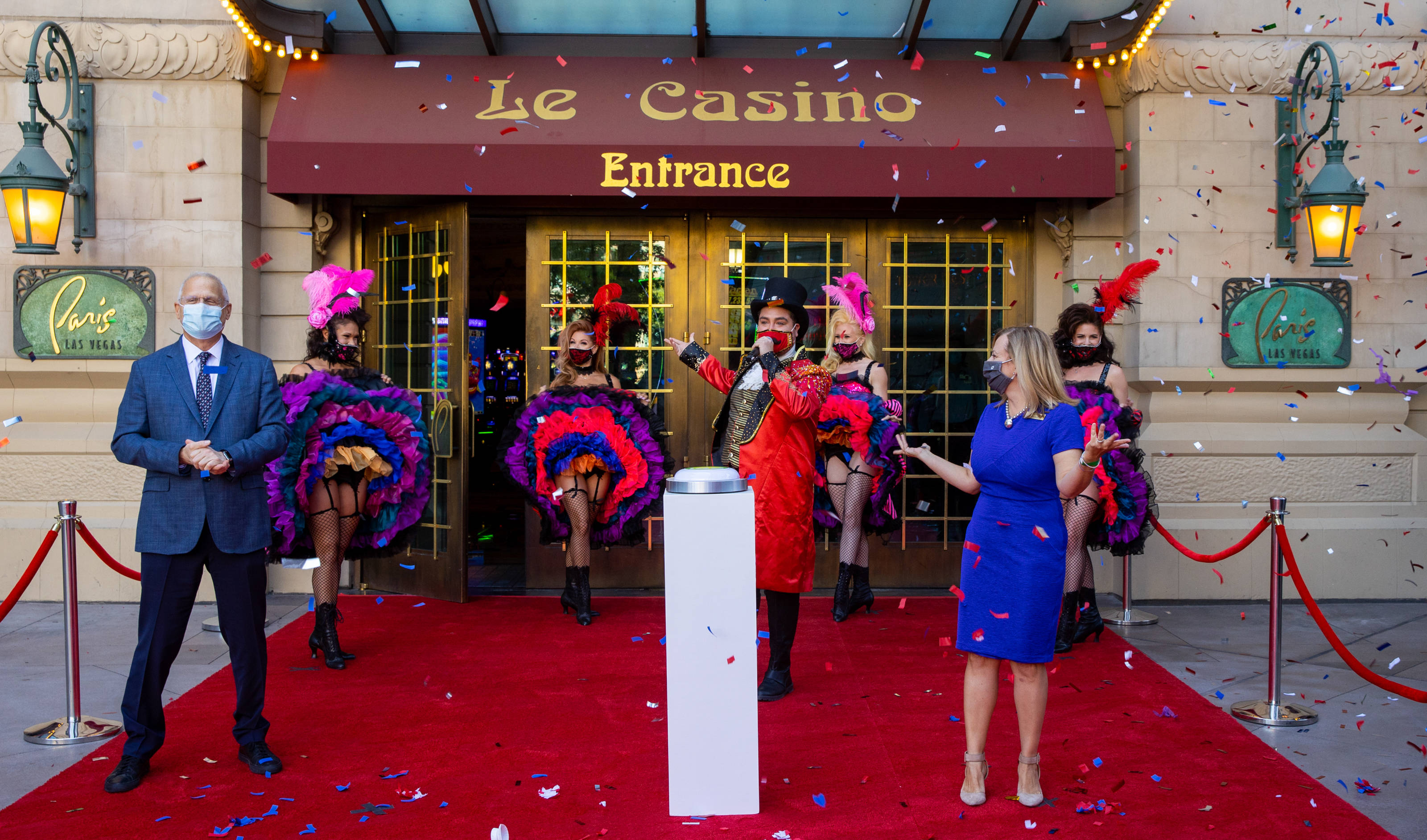Casino 桌布 壁紙 — 兩名戴面具的官員站在羽毛表演者兩旁，紙屑如雨般灑落在Le Casino的正門入口。