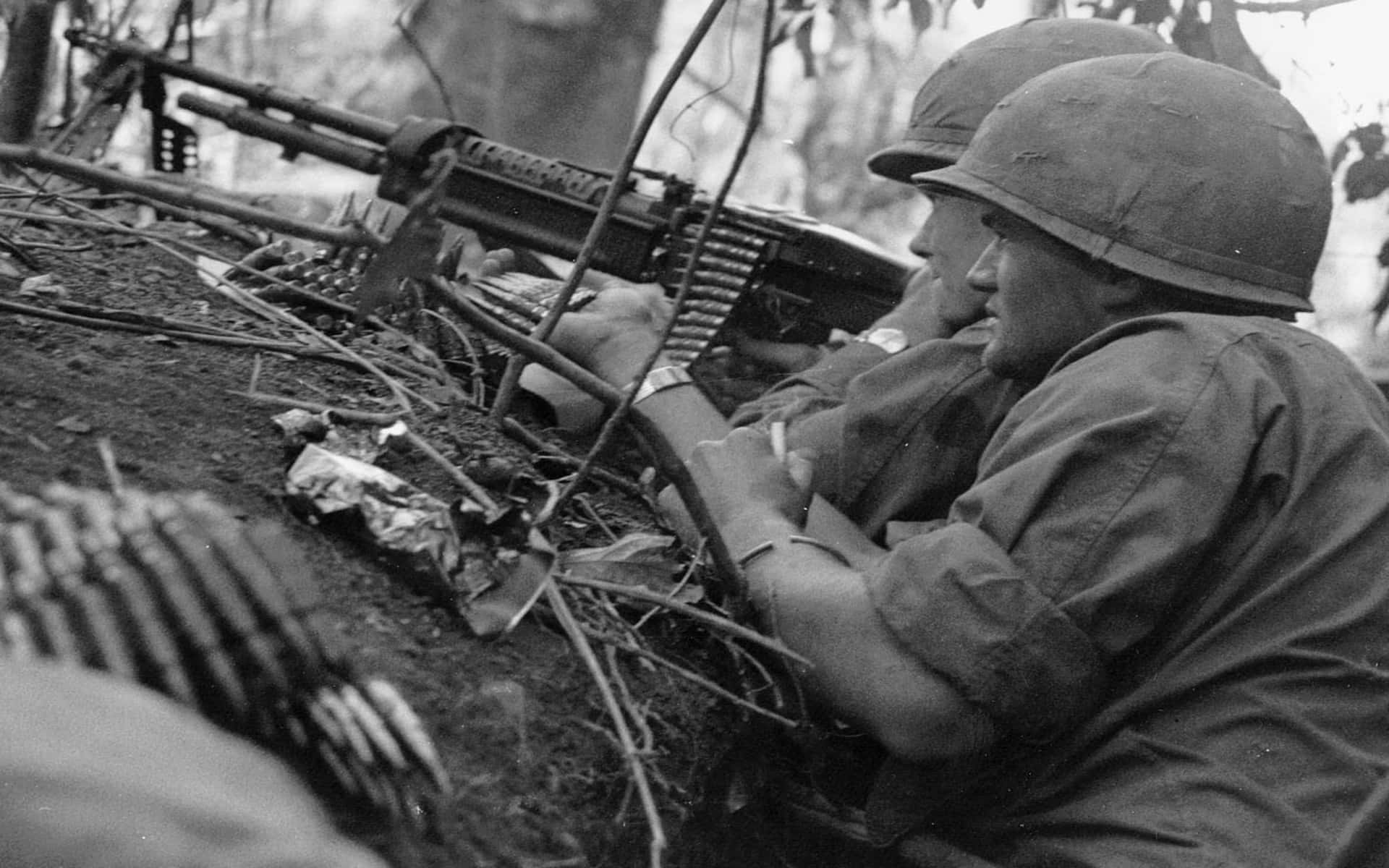 Vietnam War 桌布 壁紙 — 兩名戴頭盔的士兵在叢林戰壕中瞄準機槍，照片呈粗糙的黑白風格。