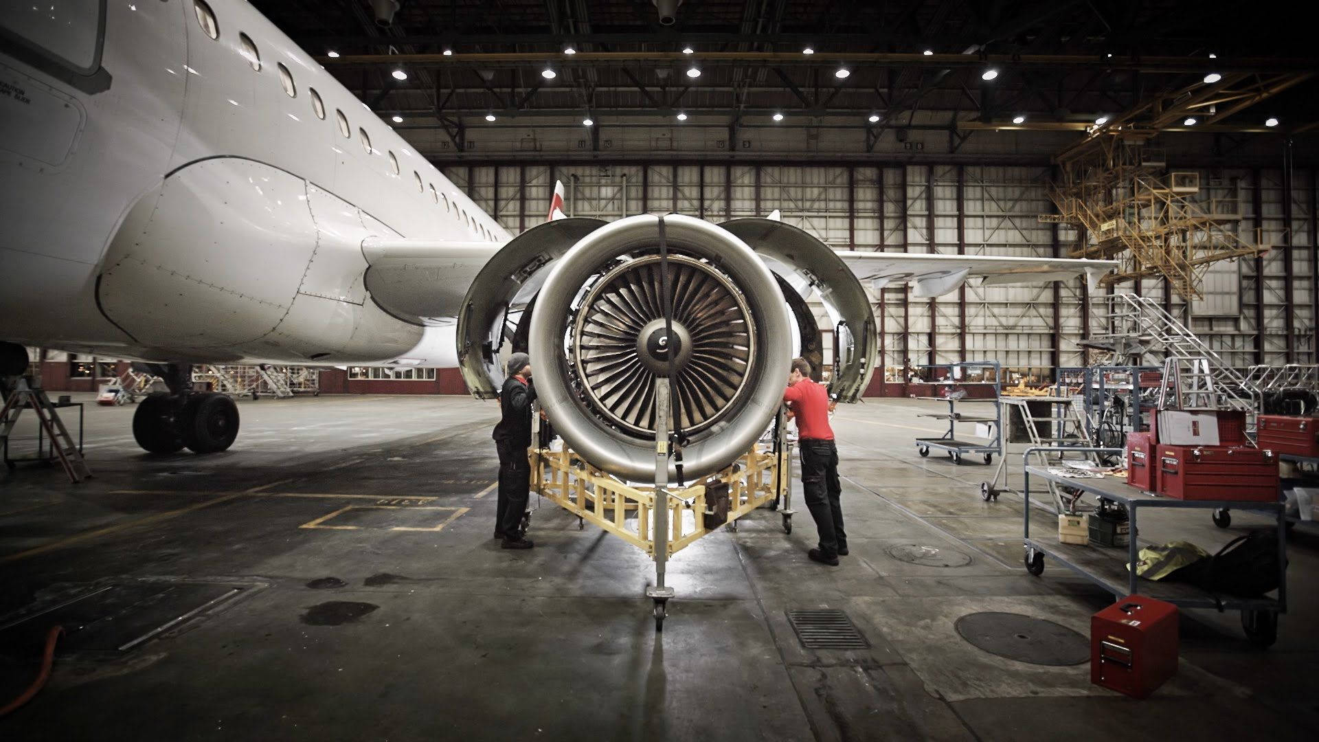 Maintenance 桌布 壁紙 — 兩名技術人員在寬敞的飛機庫內維修大型噴射引擎，背景可見飛機機身。