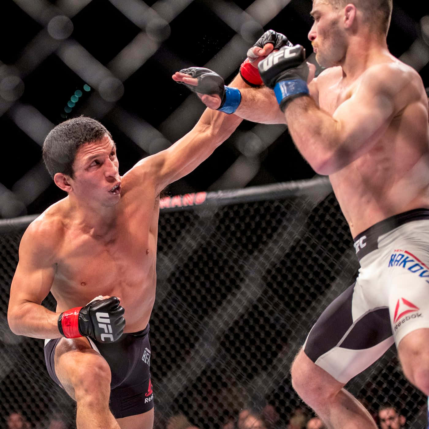 MMA 桌布 壁紙 — 兩名拳手在UFC八角籠中交鋒，一人打出強力一拳，另一人則進行格擋。
