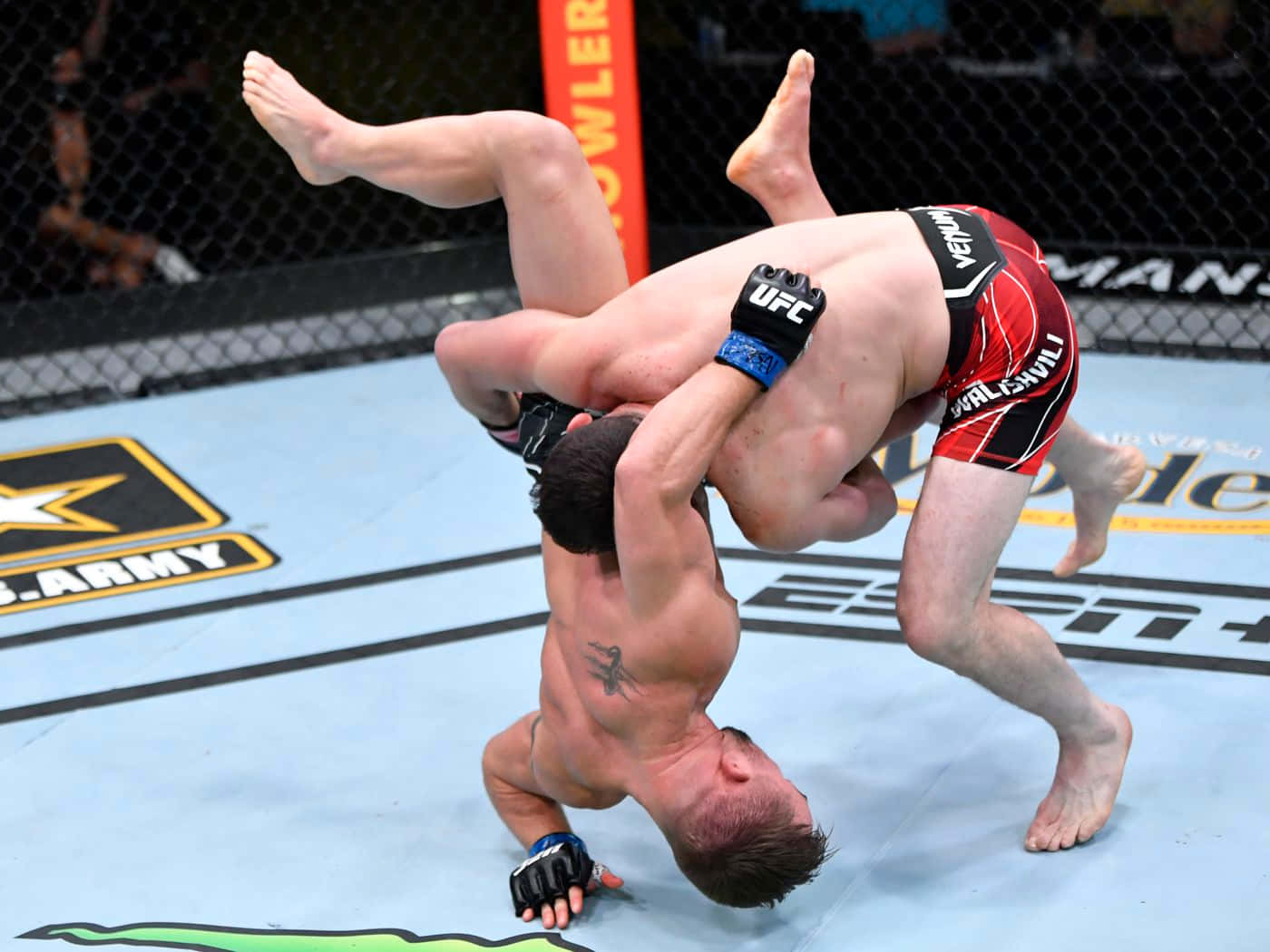 桌布 壁紙 — 兩名拳手在UFC八角籠中激烈纏鬥，其中一人施展出一個動態的腿部鎖定降服技。