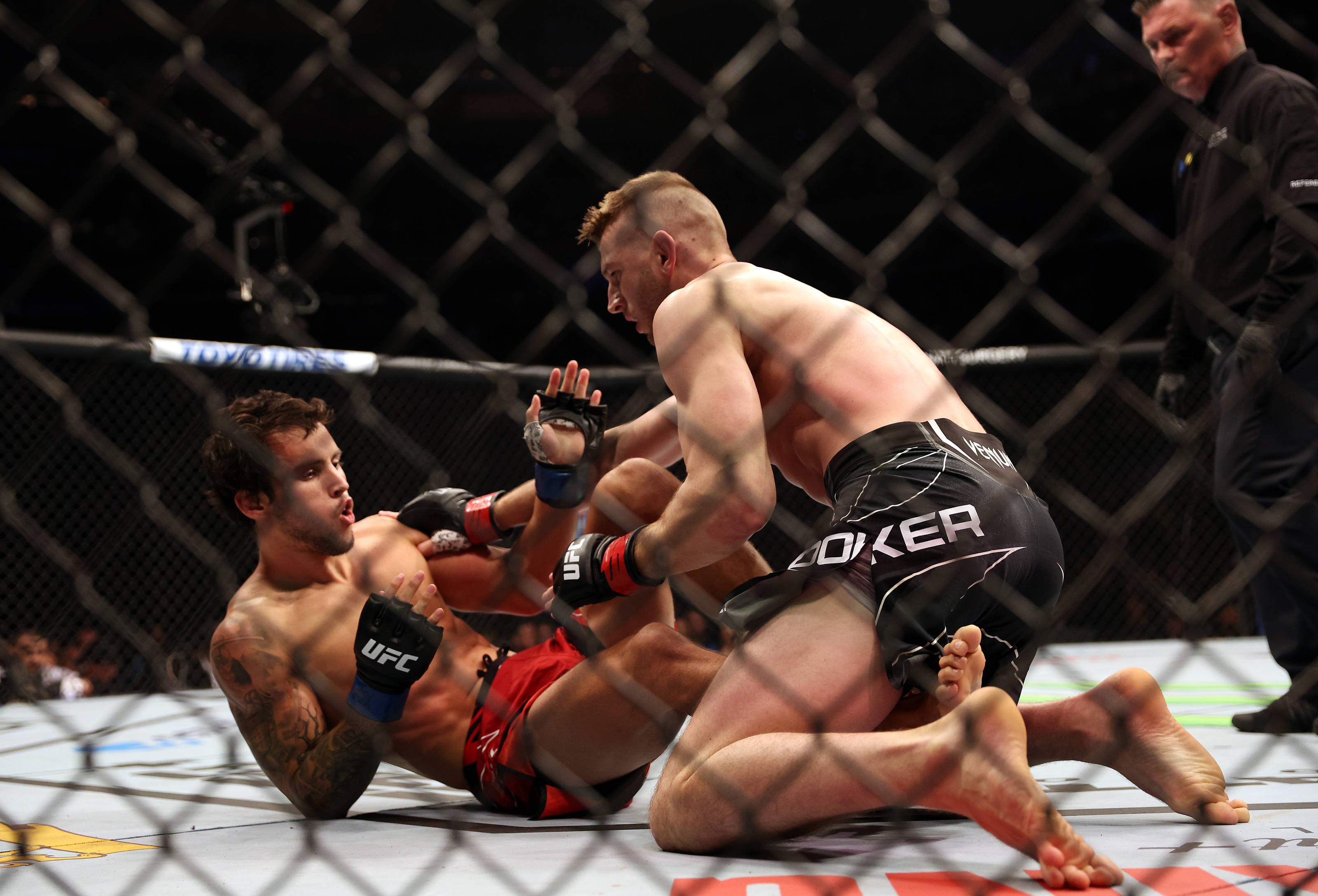 UFC 桌布 壁紙 — 兩名拳手在UFC八角籠內激烈纏鬥，裁判在旁緊密注視。