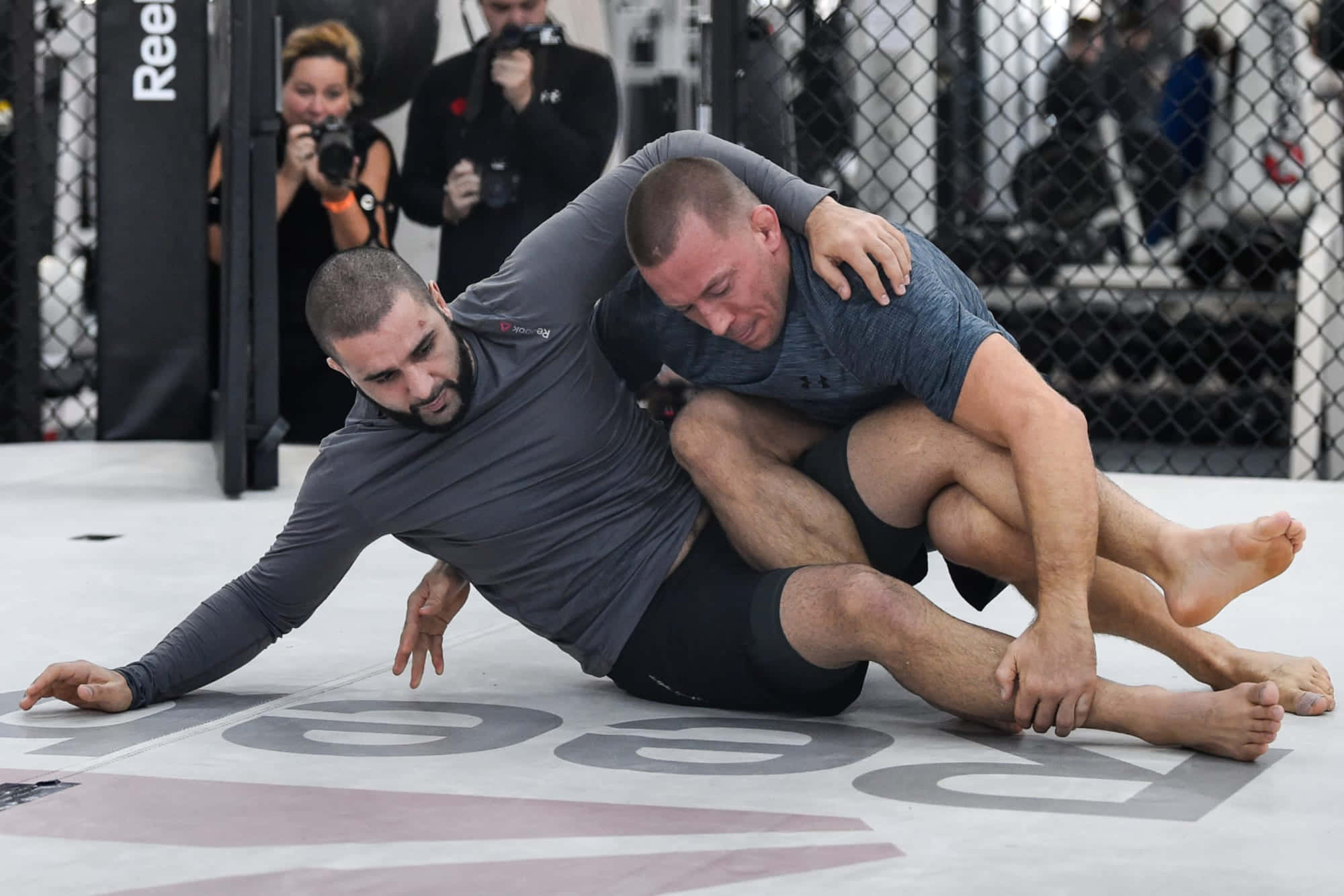Coach 桌布 壁紙 — 兩名拳手在UFC八角籠墊上激烈纏鬥，攝影師捕捉動作。