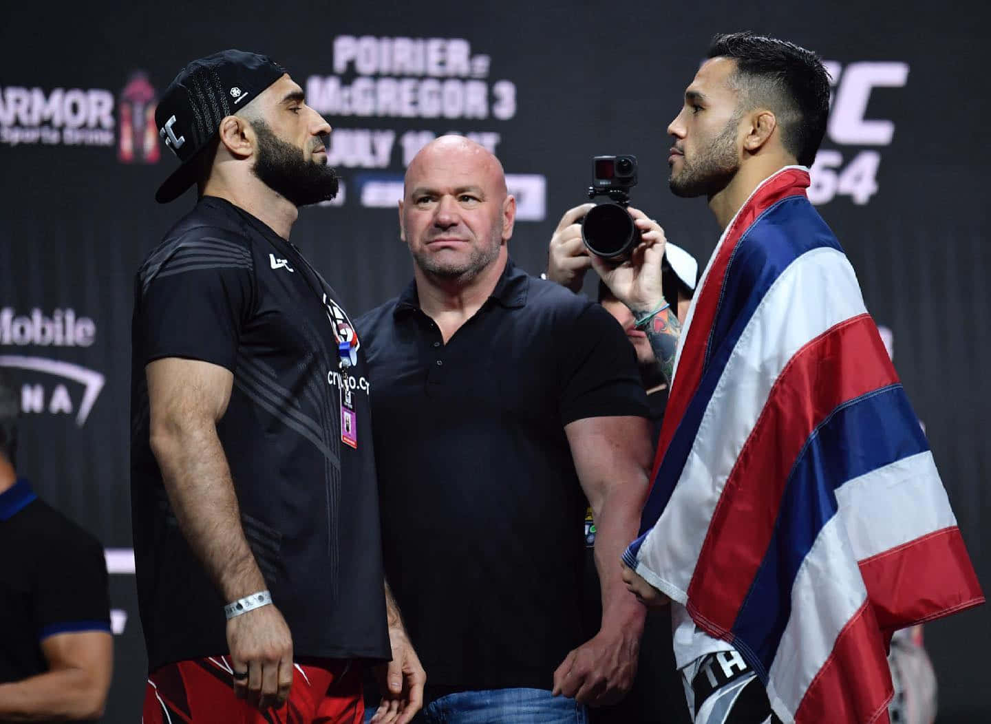 UFC 桌布 壁紙 — 兩名拳手在UFC過磅中對峙，中間有裁判，相機捕捉緊張時刻。