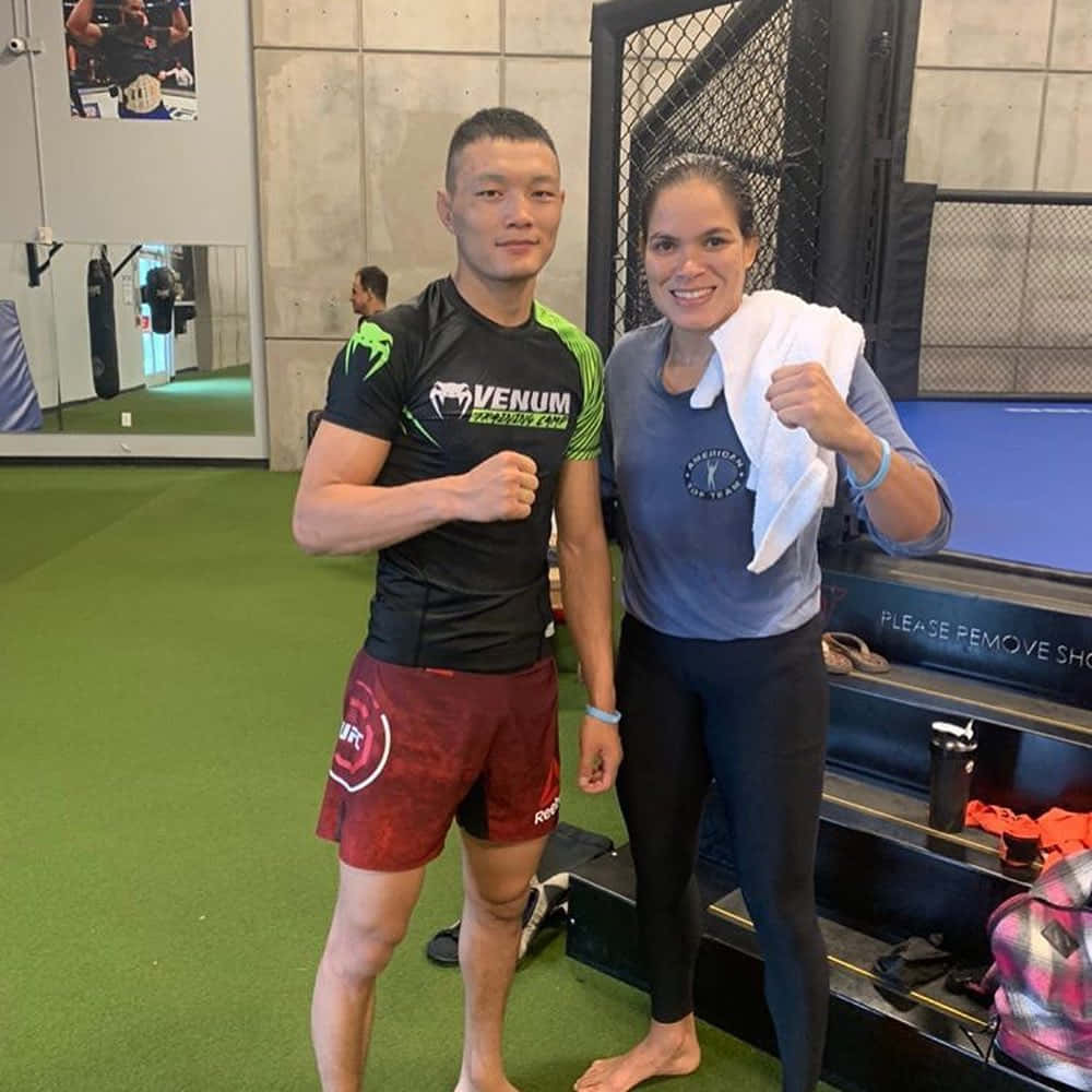 MMA 桌布 壁紙 — 兩名拳手在健身房自信地擺姿勢，身後有鐵籠和鏡子。