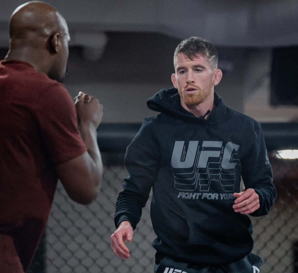 MMA 桌布 壁紙 — 兩名拳手在昏暗的八角籠中對峙，鐵絲網圍欄，神情專注。
