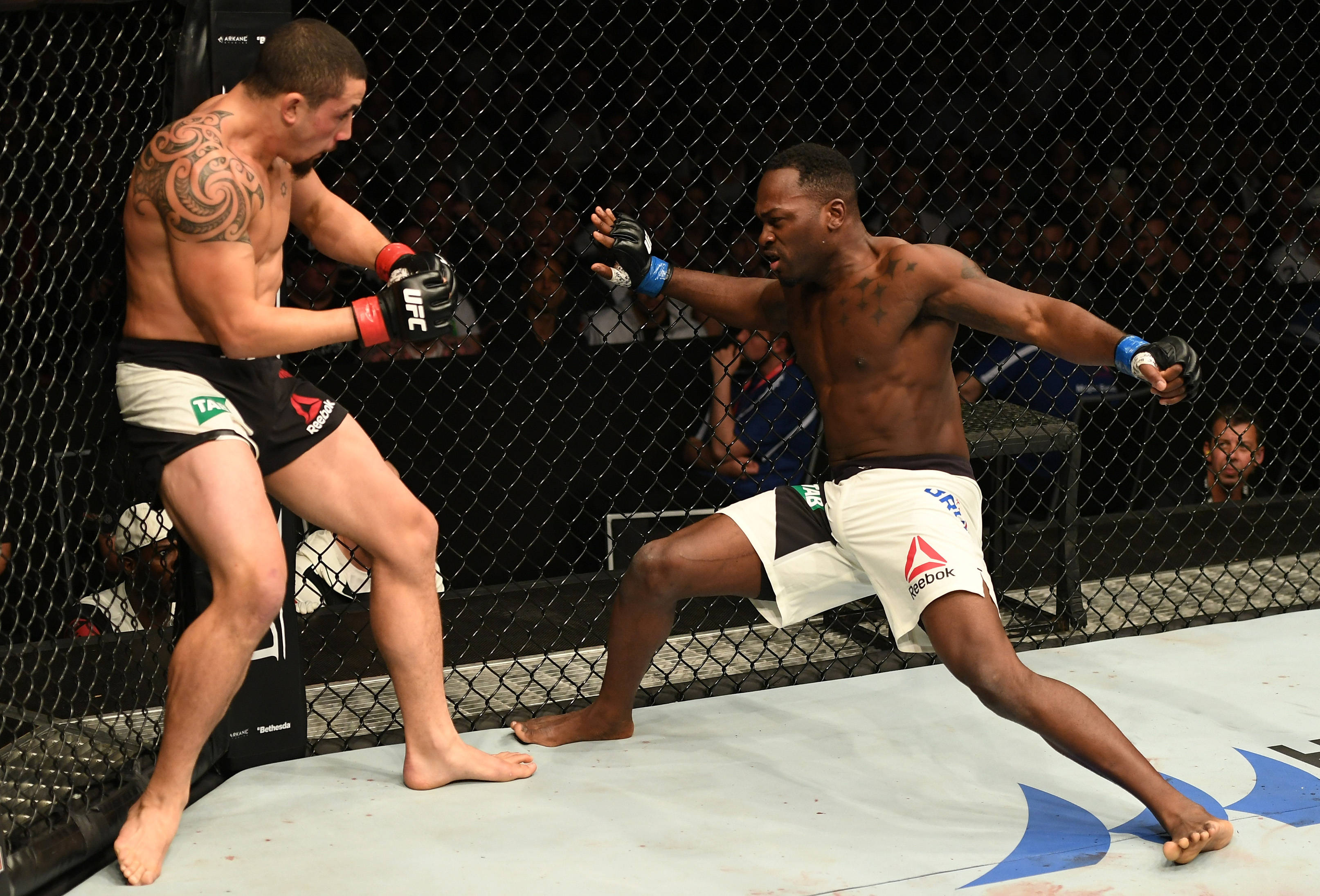 Athletic 桌布 壁紙 — 兩名拳手在籠中交鋒，一人出拳，另一人防守，進行一場高風險的MMA比賽。