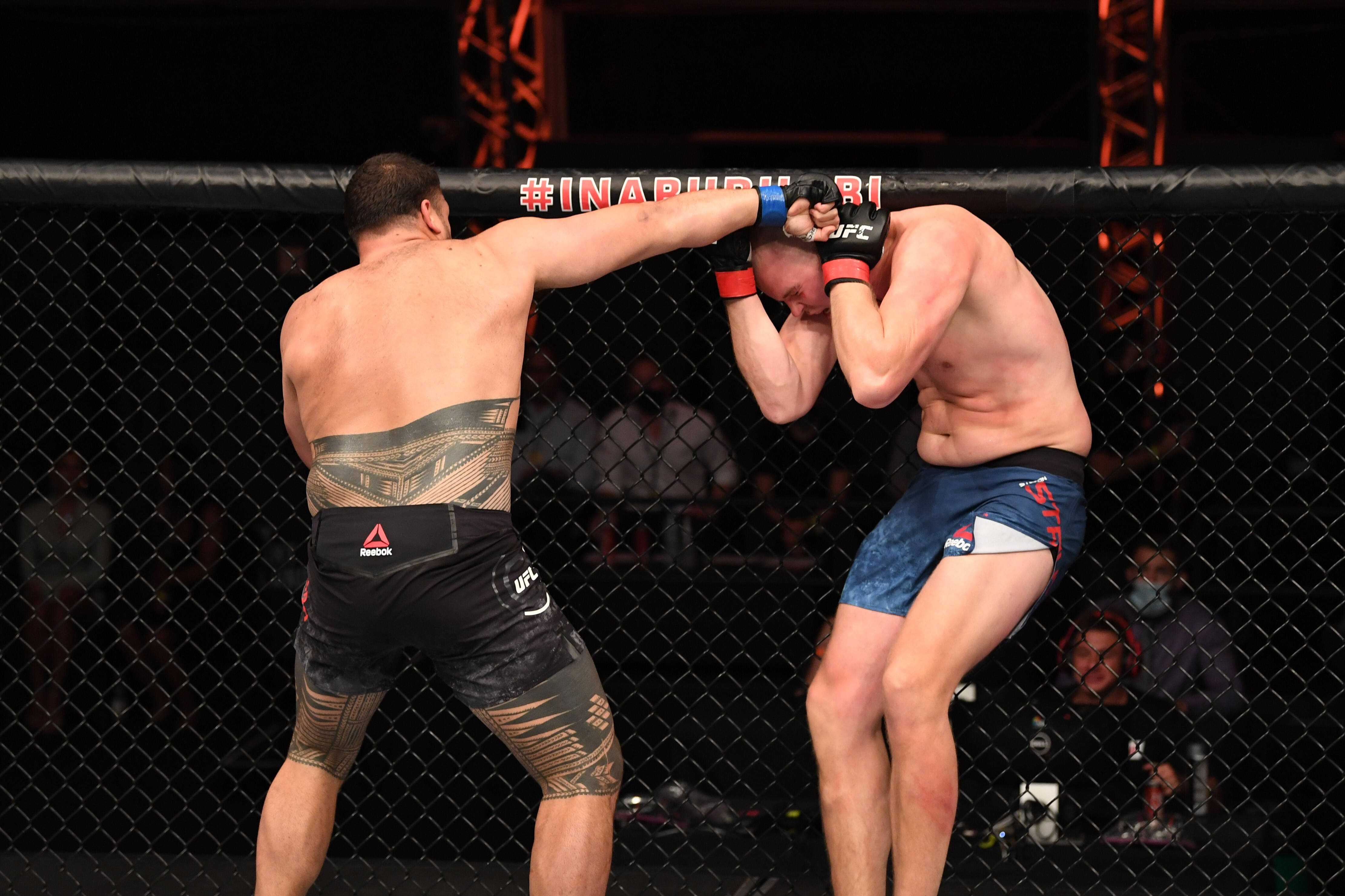 運動 桌布 壁紙 — 兩名拳手在籠中交鋒，其中一人在 UFC 比賽中對對手的頭部打出強力一拳。