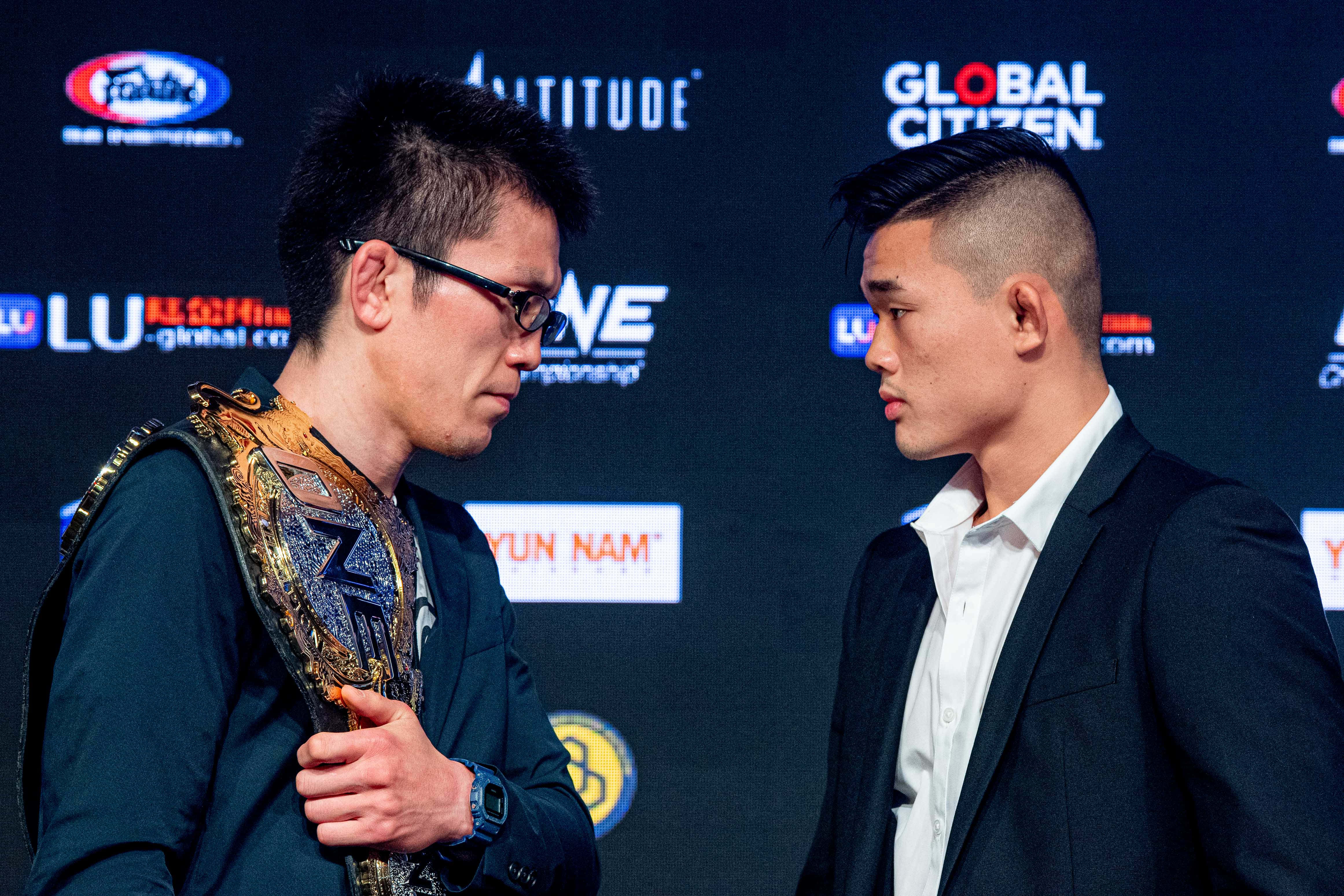 martial arts 桌布 壁紙 — 兩名拳手在記者會上對峙，一人手持冠軍腰帶，另一人則怒目而視。