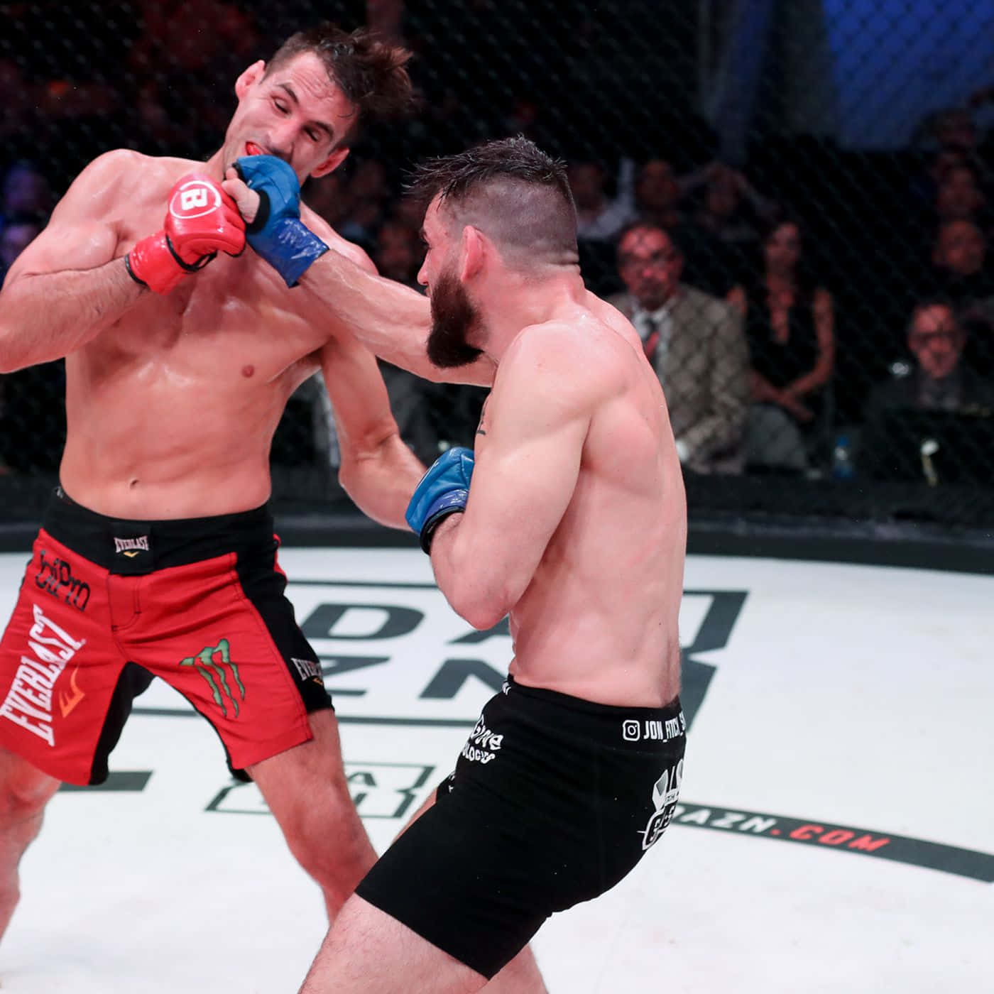 UFC 桌布 壁紙 — 兩名拳手在鐵籠中激烈交鋒，其中一人向對方臉部揮出一拳，這是一場高強度的MMA比賽。
