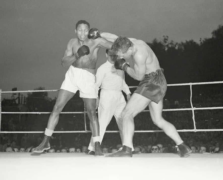 Boxing 桌布 壁紙 — 兩名拳擊手在一場緊張的擂台比賽中交鋒，裁判在旁仔細觀看，這是一張復古黑白照片。