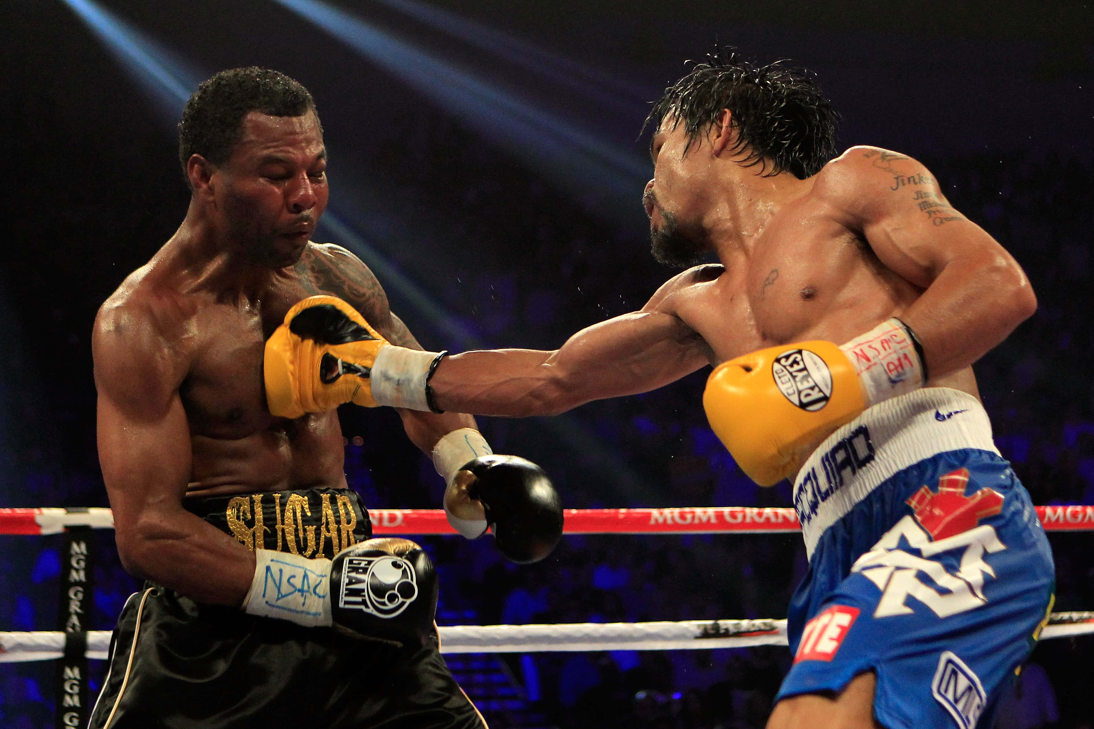 Boxing 桌布 壁紙 — 兩名拳擊手在戲劇性的擂台上碰撞，汗水飛濺，明亮的聚光燈劃破黑暗的場館。