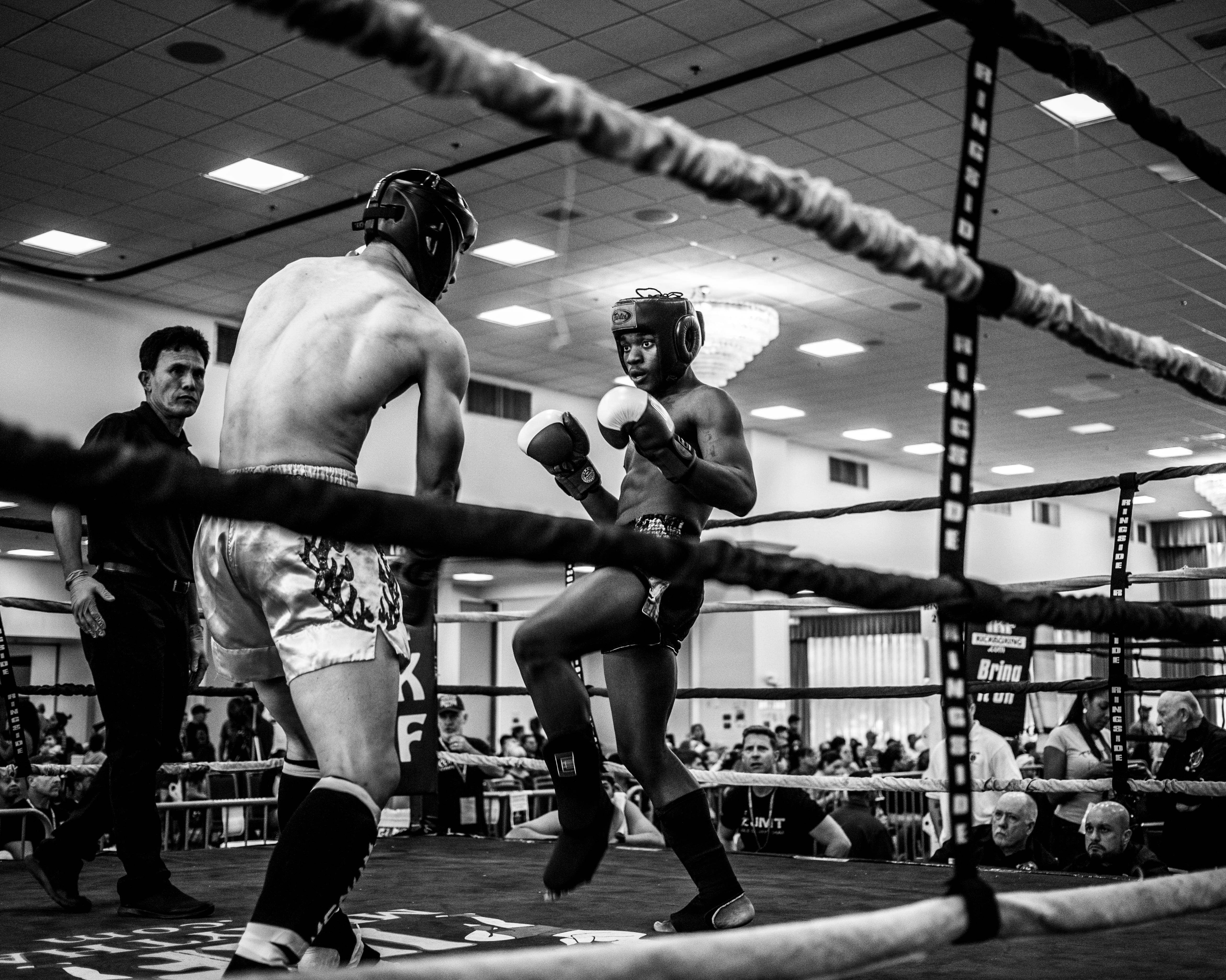 Boxing 桌布 壁紙 — 兩名拳擊手在拳擊台上，在明亮的頭頂燈光下互相出拳，觀眾專注觀看。