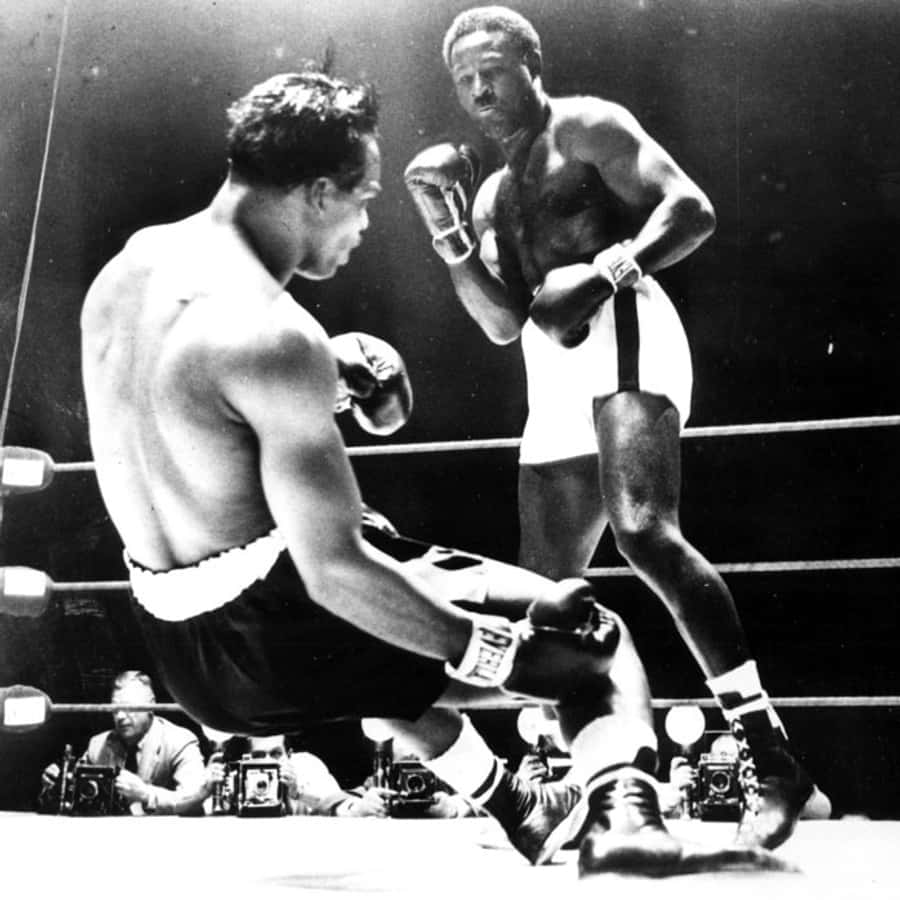 Boxing 桌布 壁紙 — 兩名拳擊手在擂台上，一人跪地，另一人站立準備在明亮的燈光下行動。