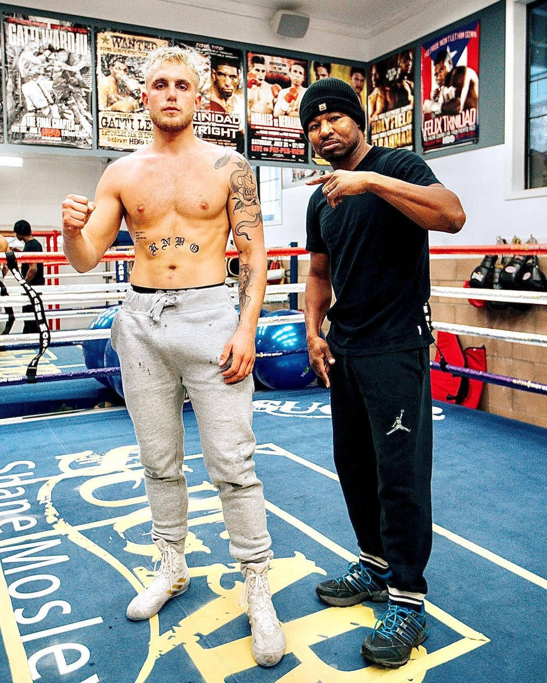 Boxing 桌布 壁紙 — 兩名拳擊手在擂台上擺姿勢，一人赤裸上身有刺青，另一人穿著黑色裝備，兩人均處於戰鬥姿勢。