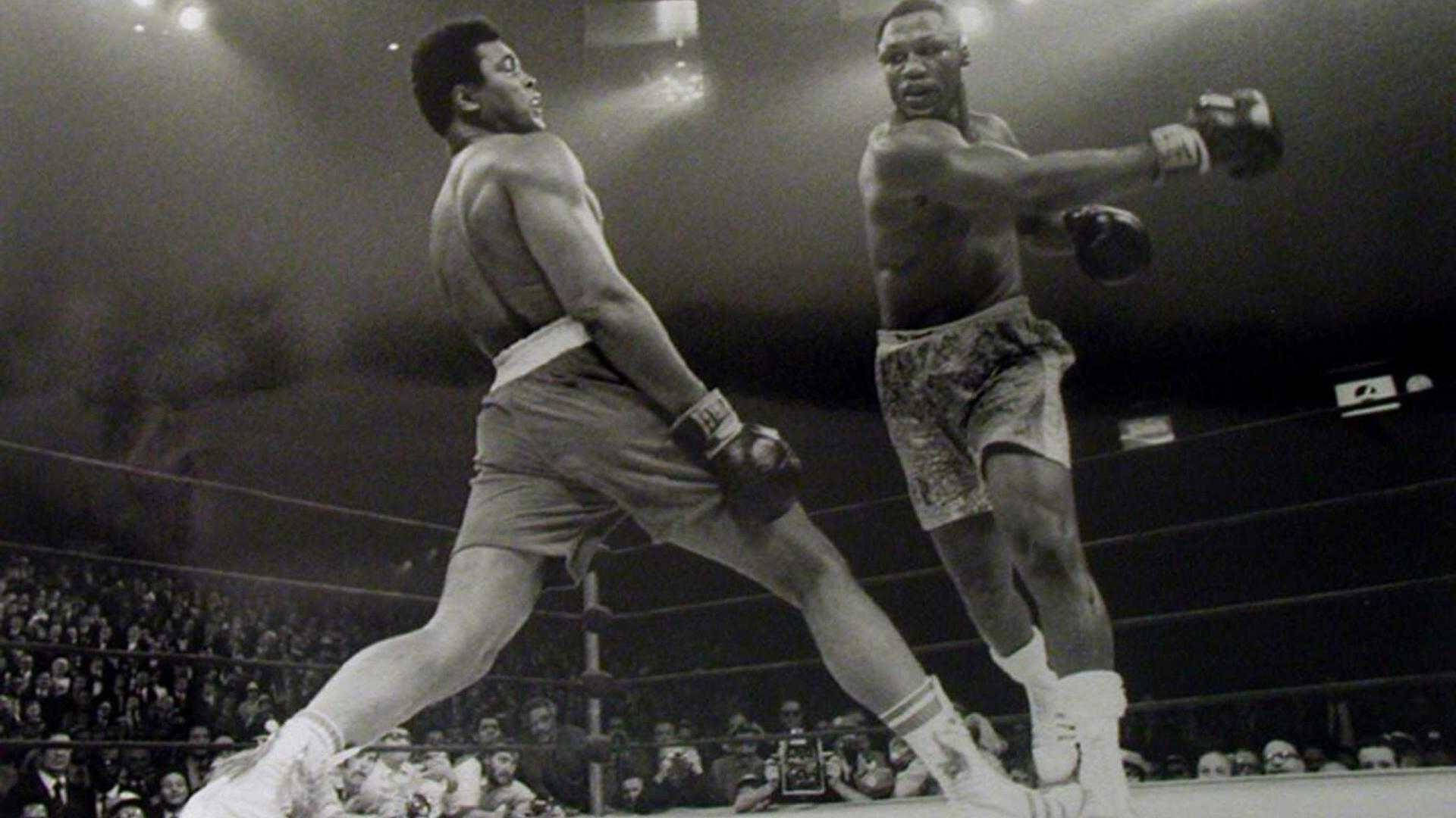 Boxing 桌布 壁紙 — 兩名拳擊手在明亮的競技場燈光下，於戲劇性的黑白拳擊場景中交鋒，周圍擠滿了專注觀看的觀眾。